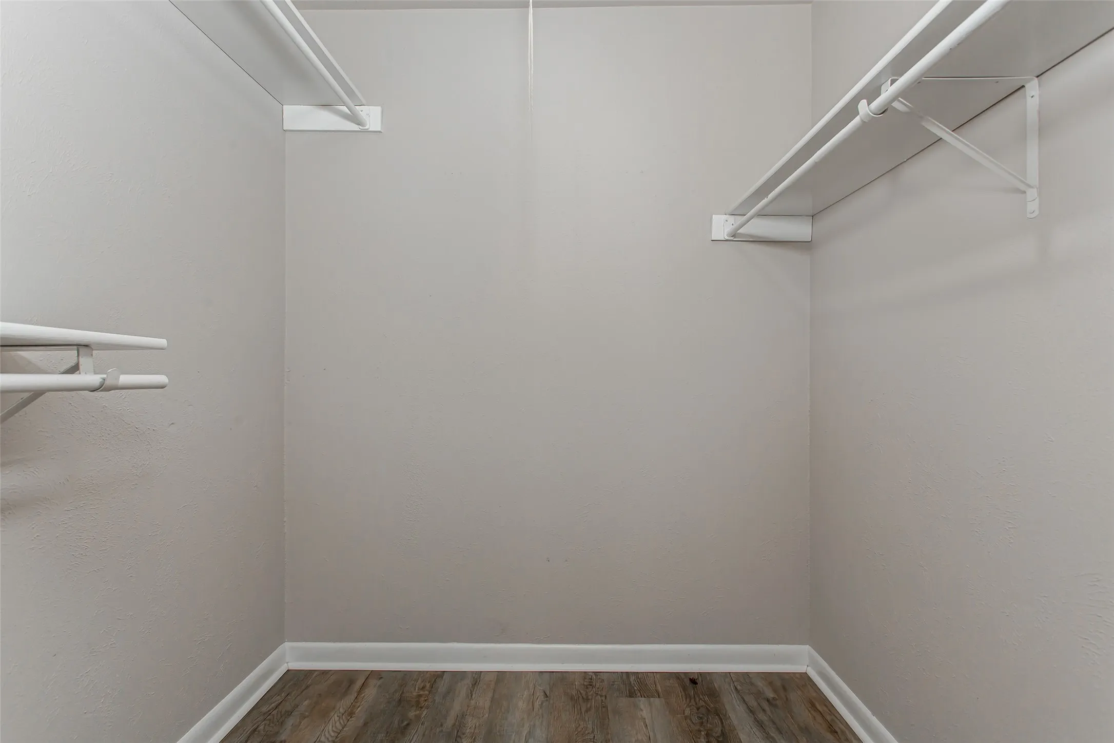 Wood-finish flooring with white baseboards and painted walls