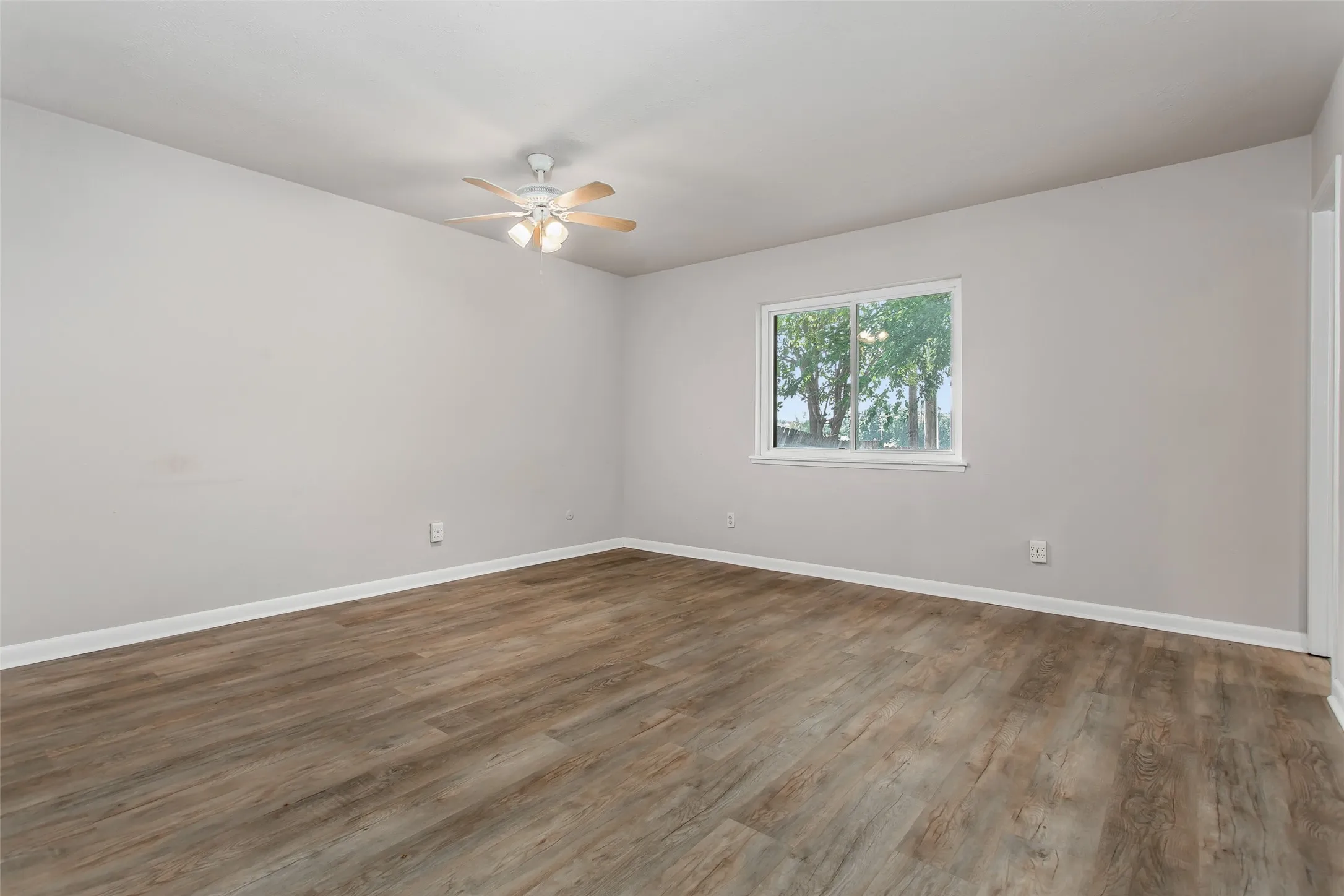 Wood-finish flooring, light neutral wall paint, and a ceiling fan with integrated lighting