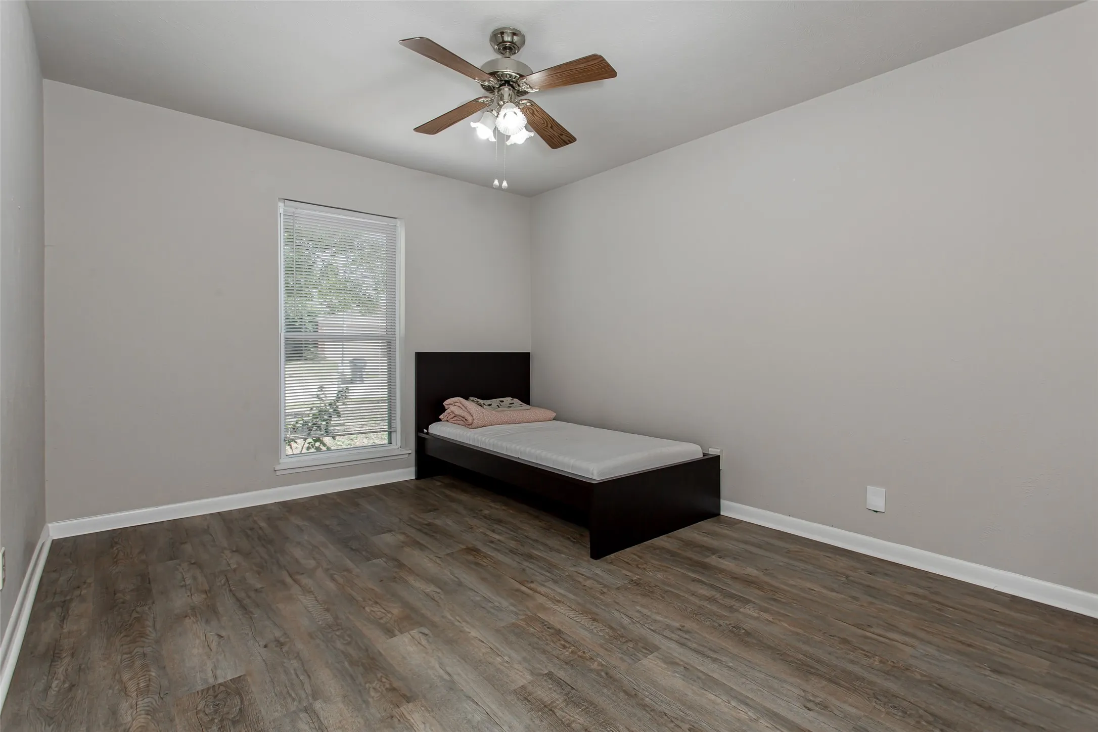 Wood-finish flooring, single window, and a ceiling fan with integrated lighting