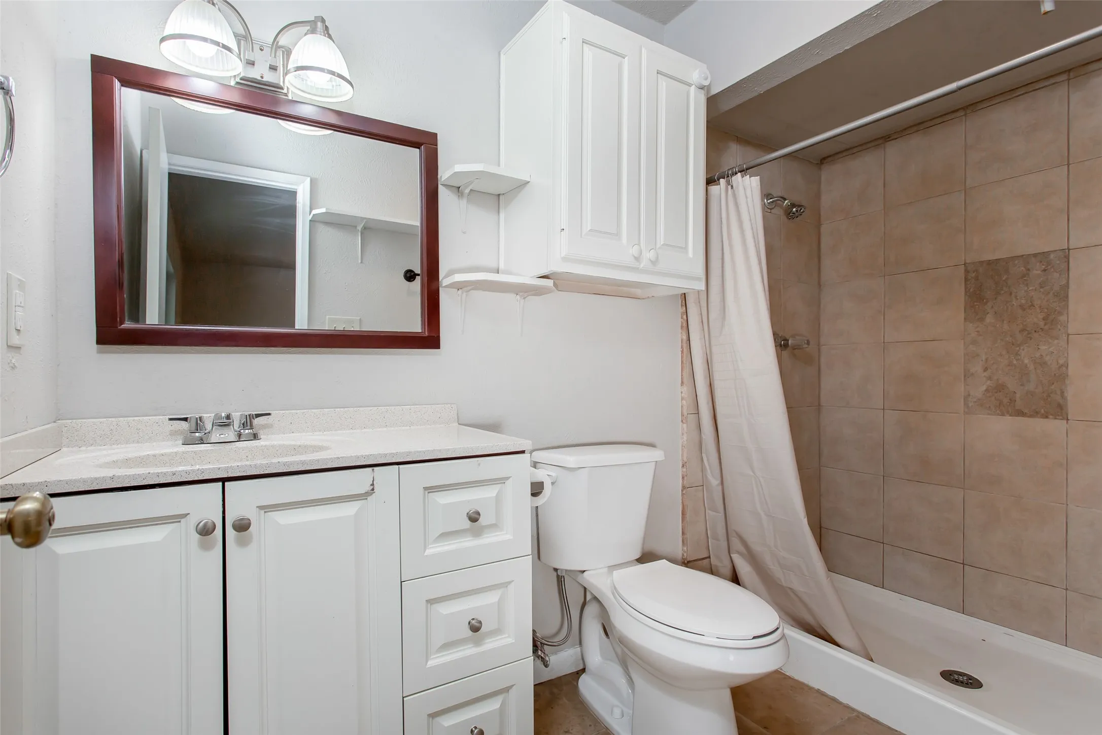 Bathroom featuring a single vanity with white cabinetry, a built-in sink, and a framed mirror