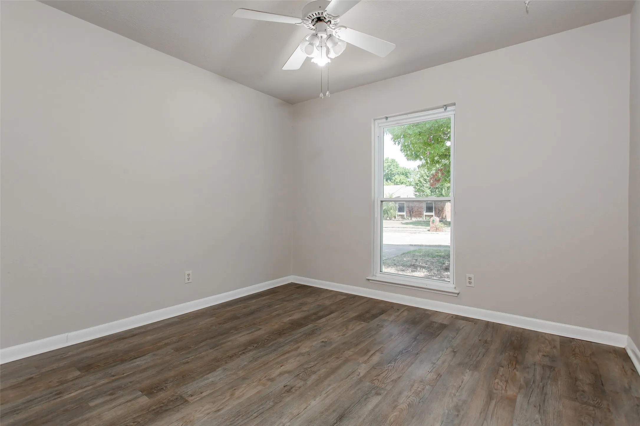 Wood-finish flooring, single window, white trim, and ceiling fan