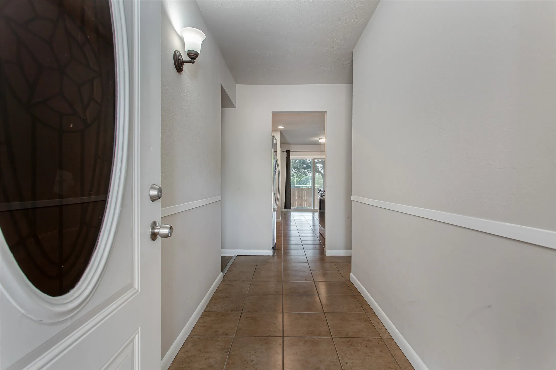 Entryway featuring tile flooring, white baseboards, and a decorative wall sconce