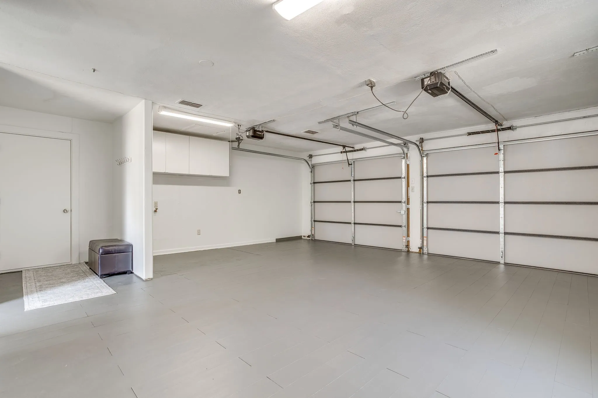 Two-car garage with overhead doors, built-in storage cabinets, and a side-entry door