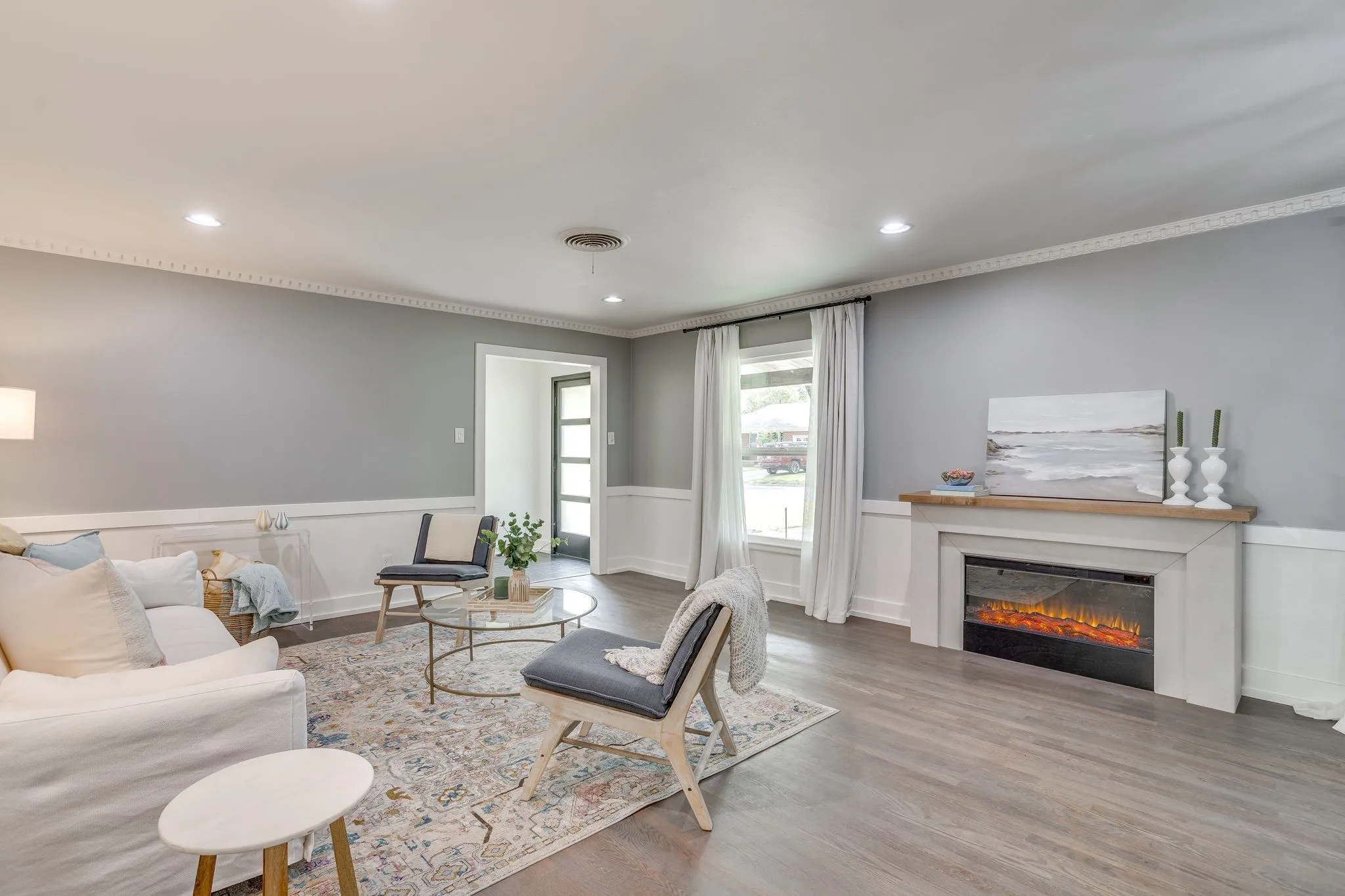 Wood-finish flooring, crown molding, chair rail molding, recessed lighting, and a built-in electric fireplace