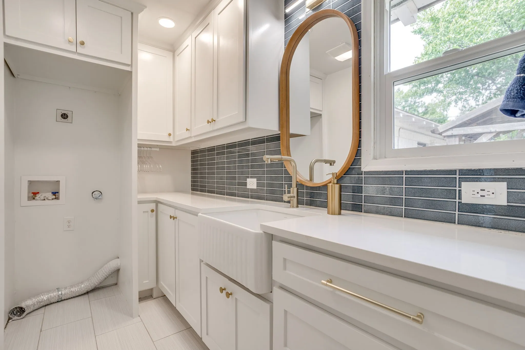 White shaker-style cabinetry with gold-finish hardware, subway tile backsplash, white countertop, and a farmhouse-style sink