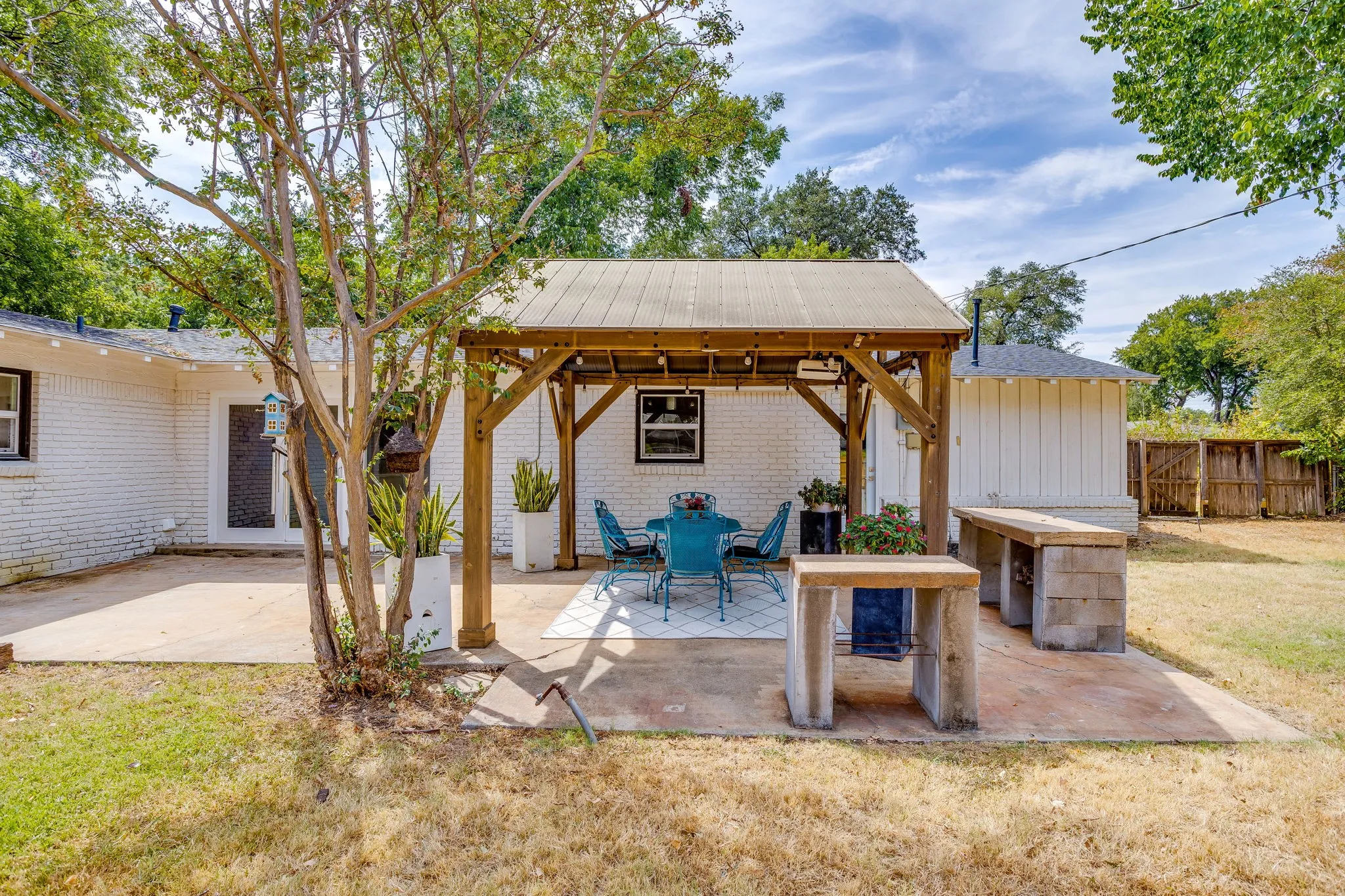 Backyard patio featuring a wood pergola, concrete patio area, and built-in masonry block outdoor counters