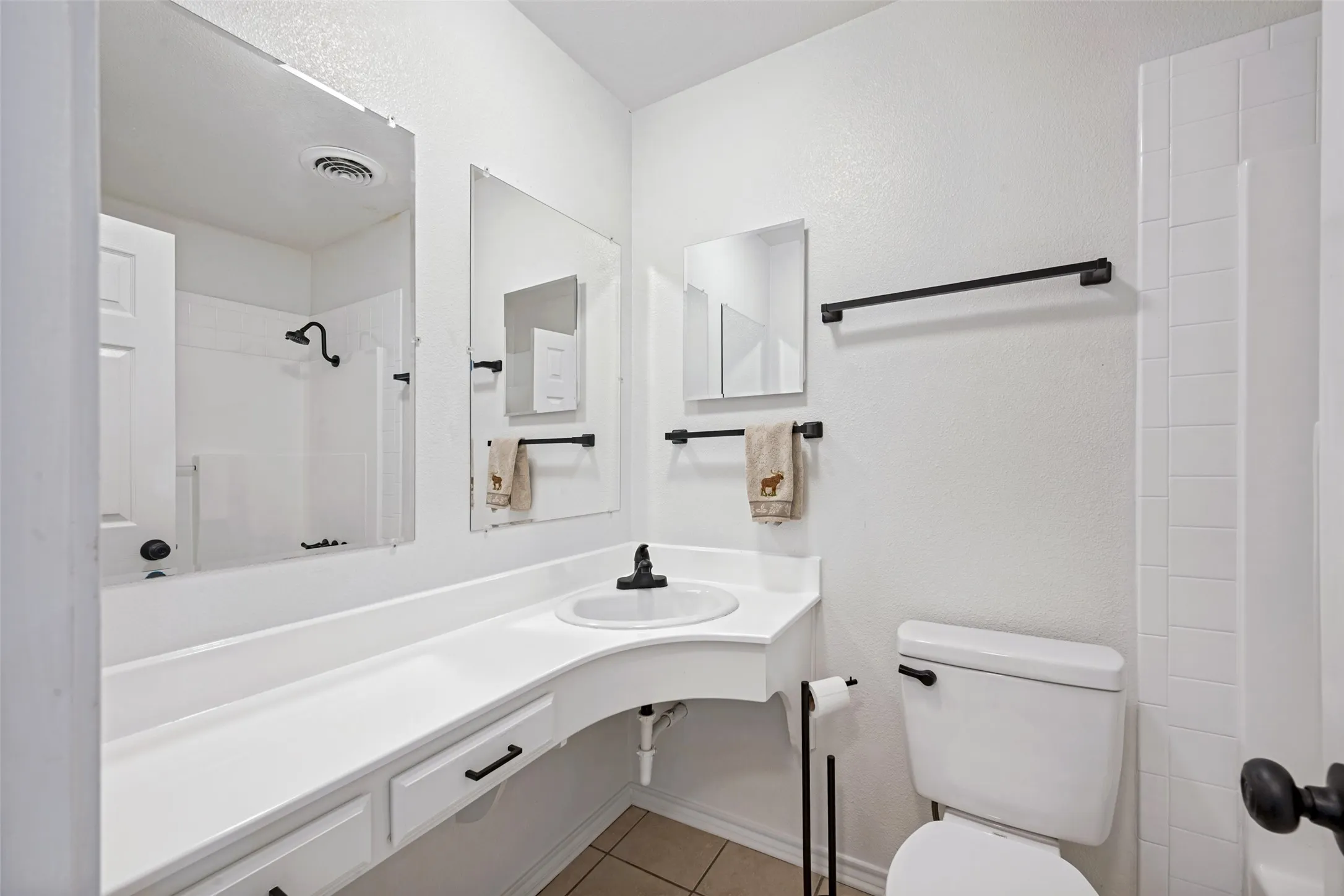 White vanity with integrated sink, black faucet, and built-in storage