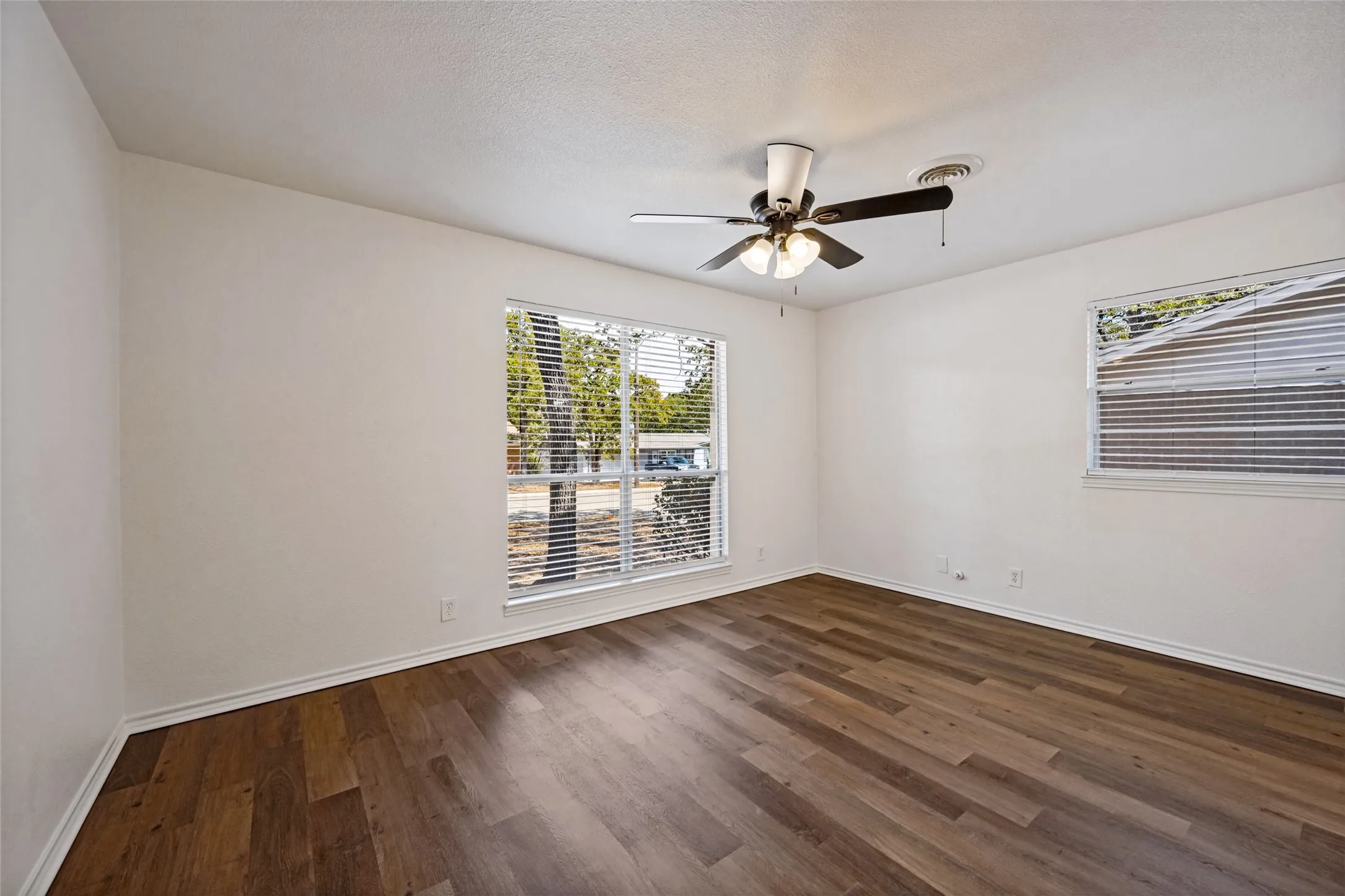 Wood-finish flooring throughout, bright white walls, and a ceiling fan with integrated lighting