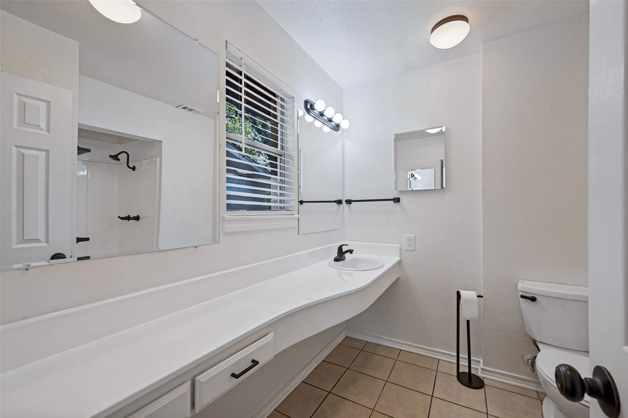 Spacious vanity with an integrated sink, matte black faucet, and built-in storage