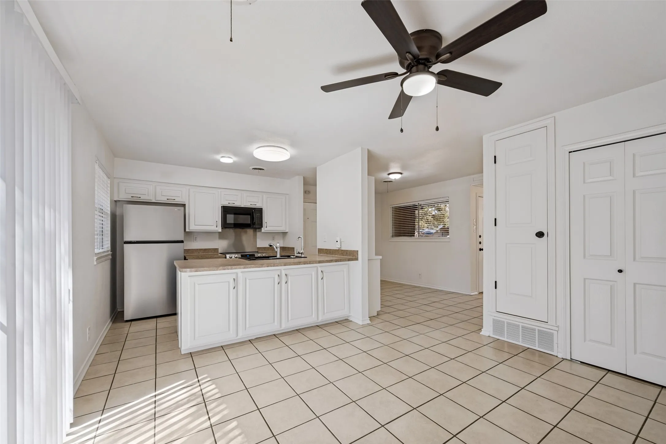 Kitchen with white cabinetry, stainless steel refrigerator, and integrated microwave