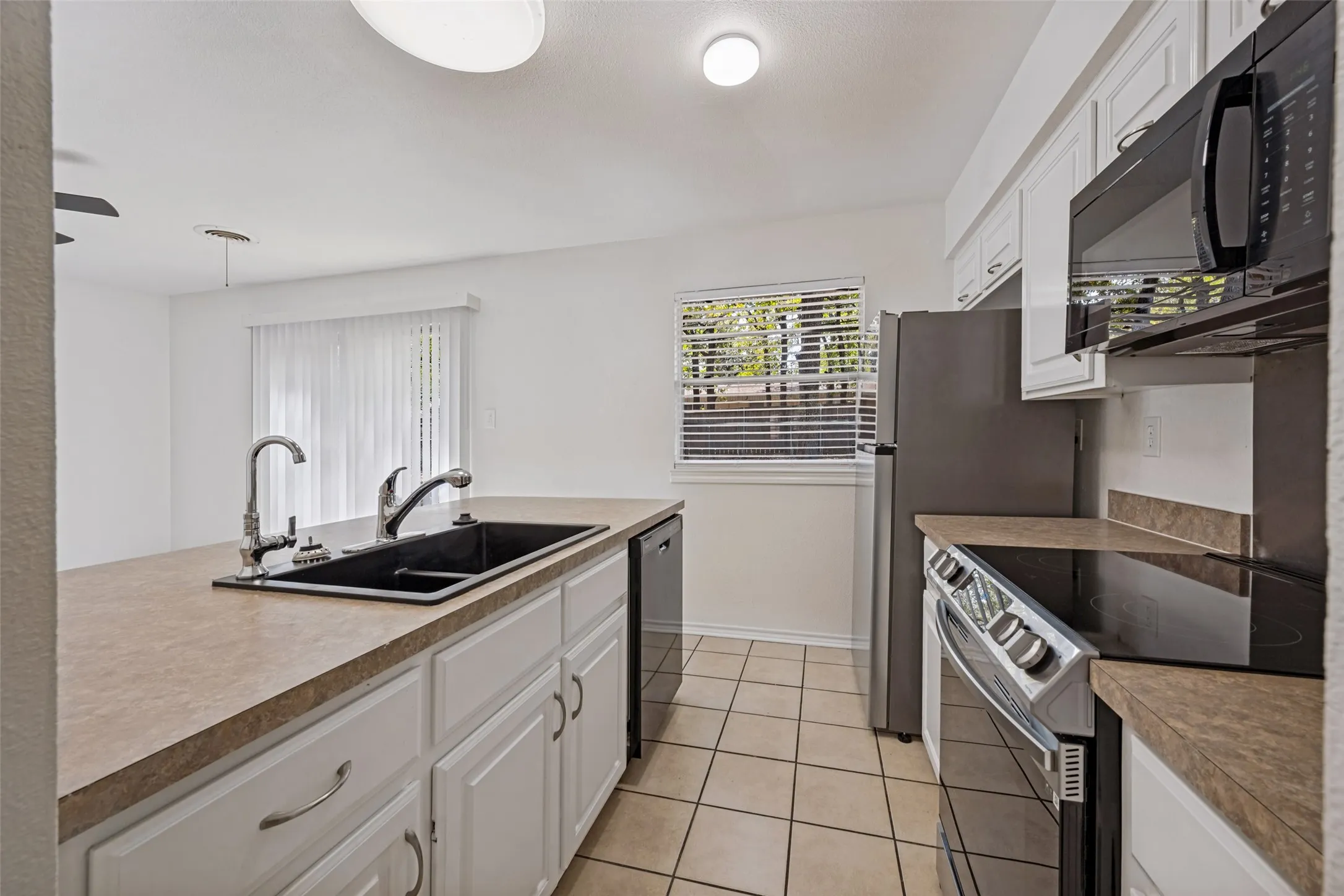 Kitchen featuring an undermount sink, white cabinetry, integrated dishwasher, and a black cooktop