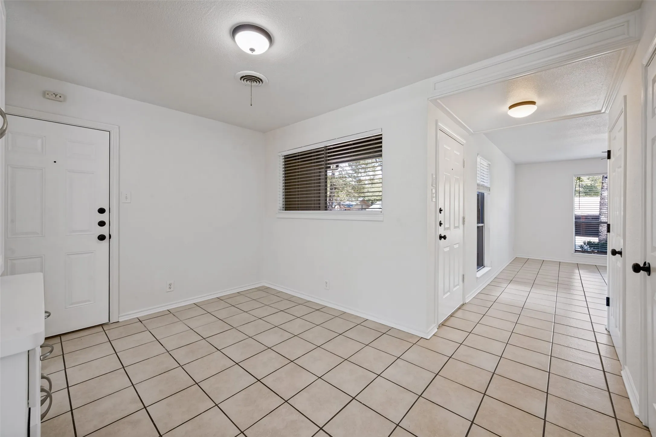 Entryway featuring tile flooring, white paneled doors, and a window with blinds
