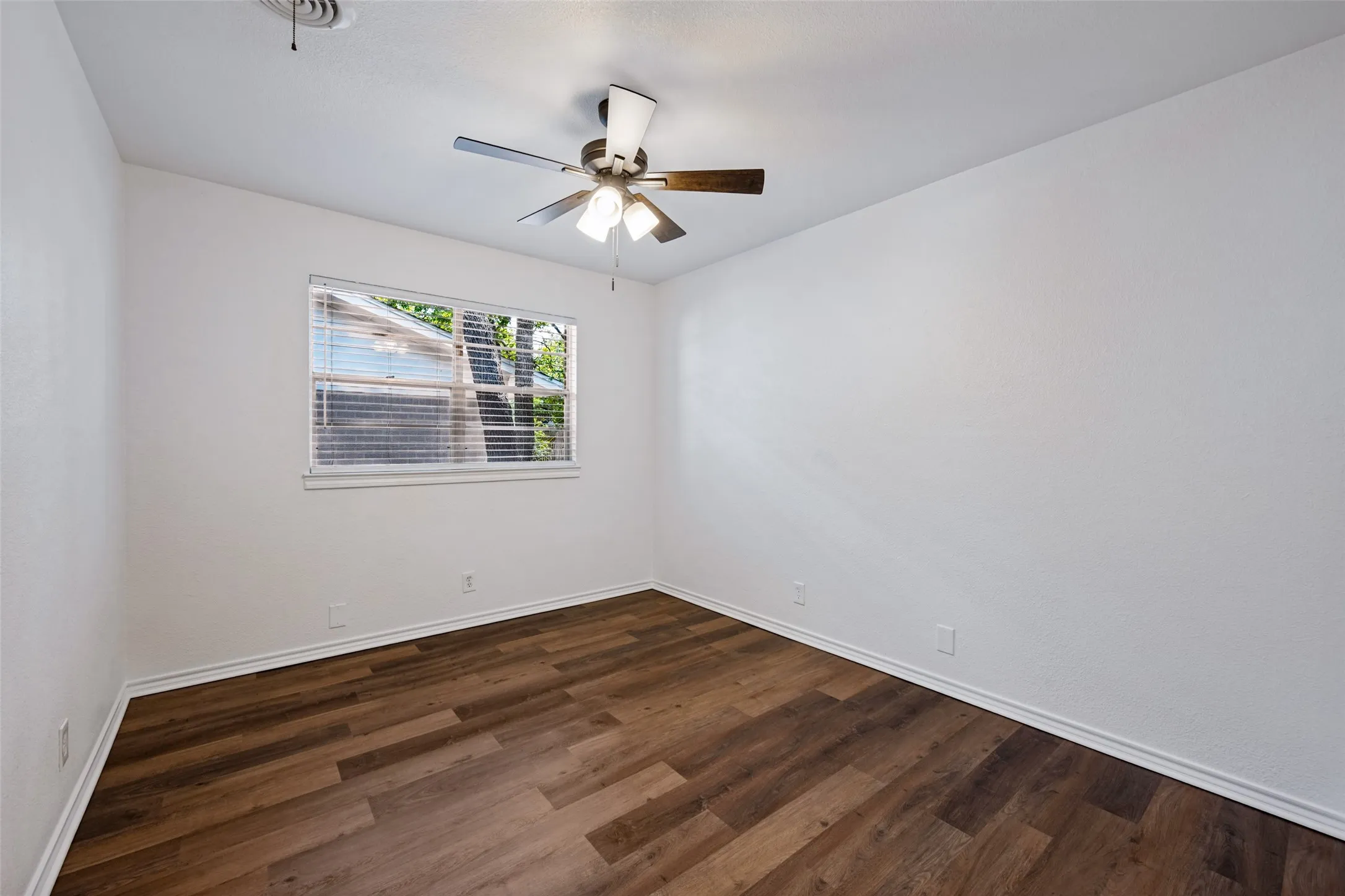 Wood-finish flooring, white walls, window with blinds, and a ceiling fan