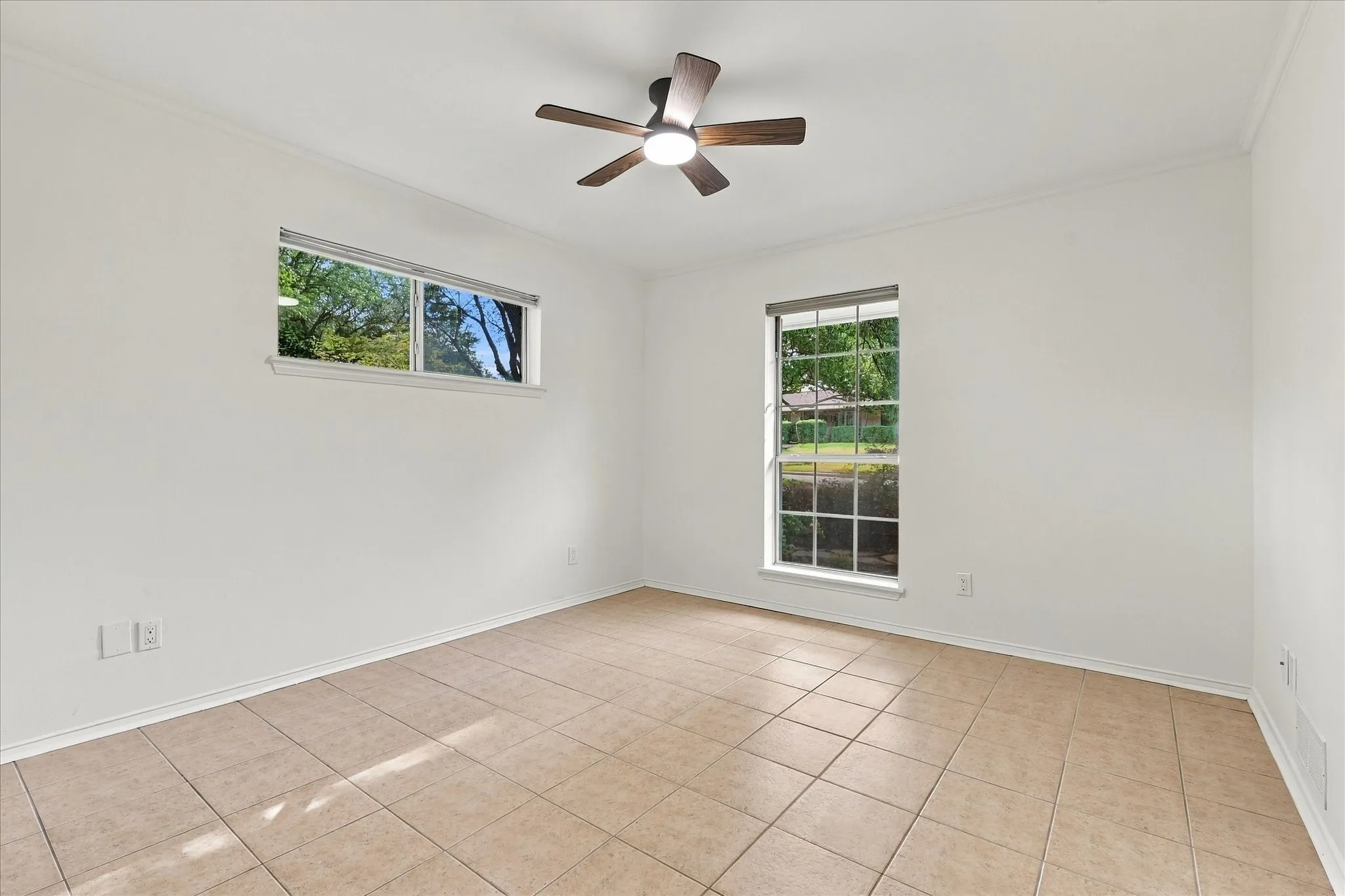 Neutral tone wall finishes, tiled flooring, two distinct windows, and a ceiling fan with integrated lighting