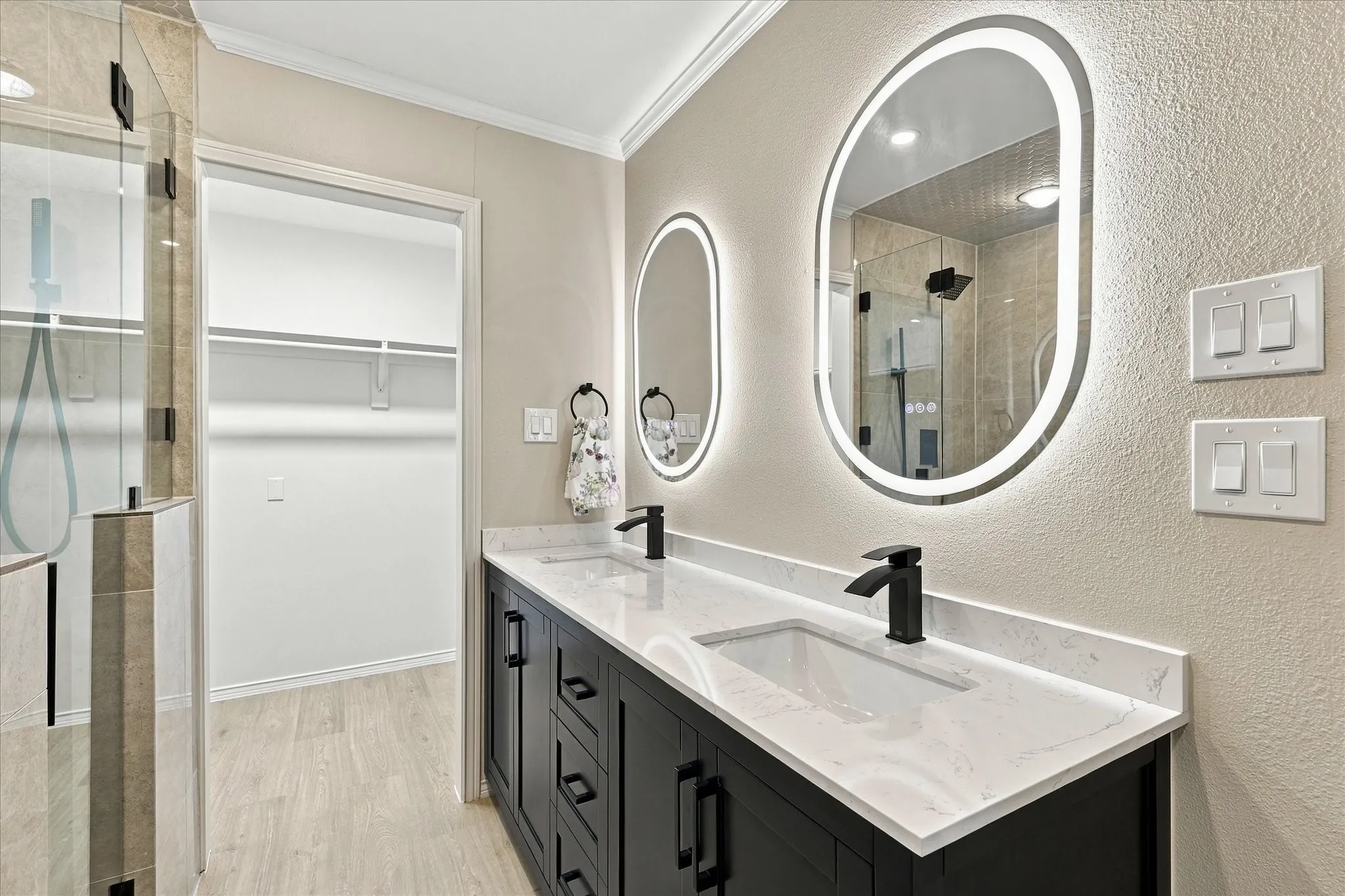 Dual vanity with quartz countertops, matte black fixtures, and lighted mirrors