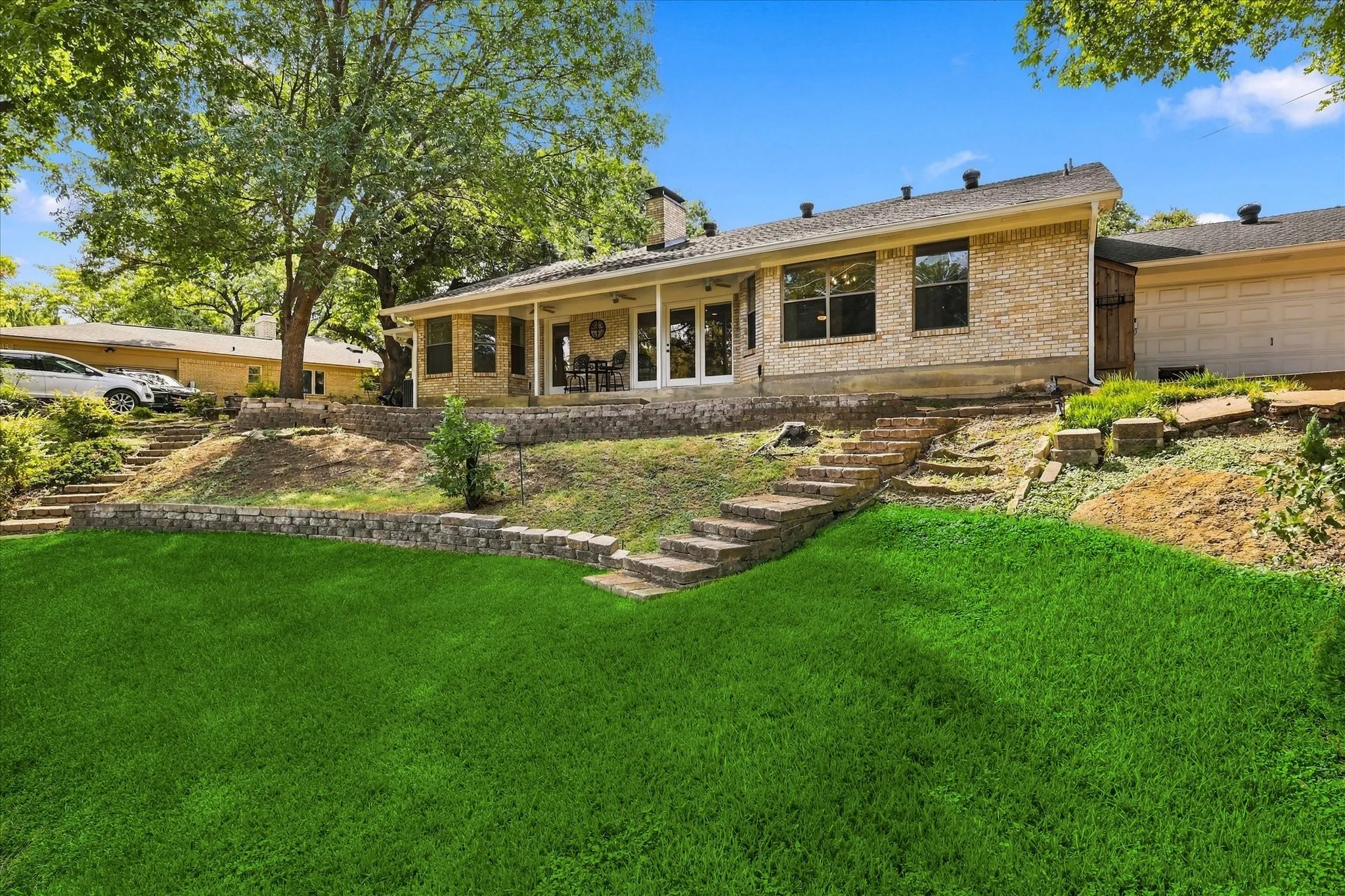 Brick exterior with a covered patio, multiple windows, and a two-car garage