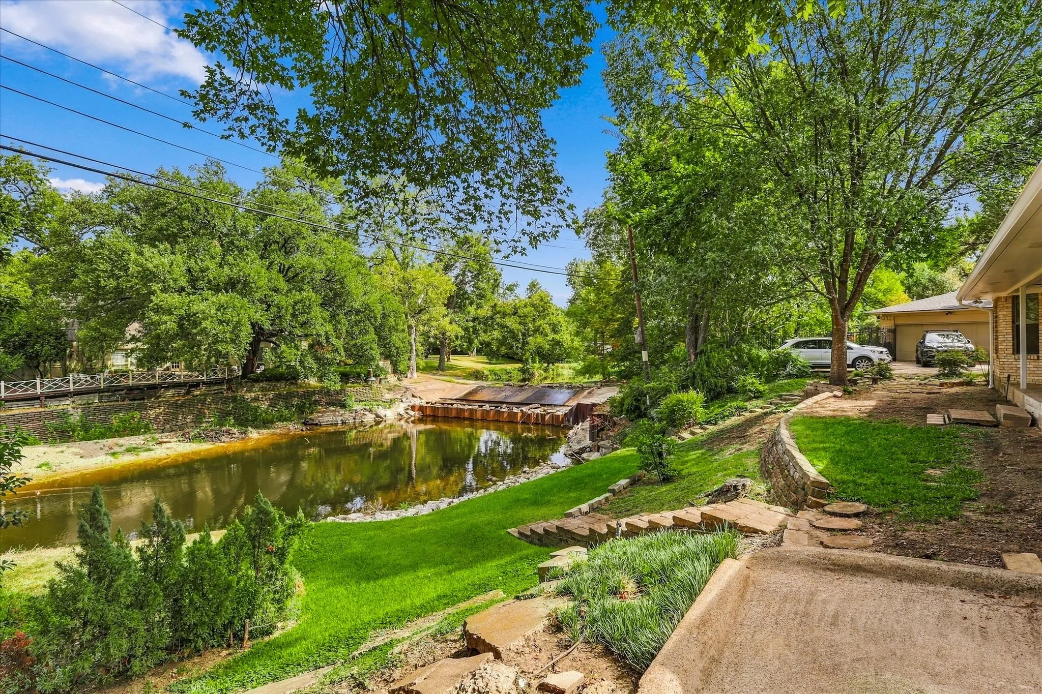 Expansive outdoor space featuring a water element, terraced landscaping, and a stone retaining wall