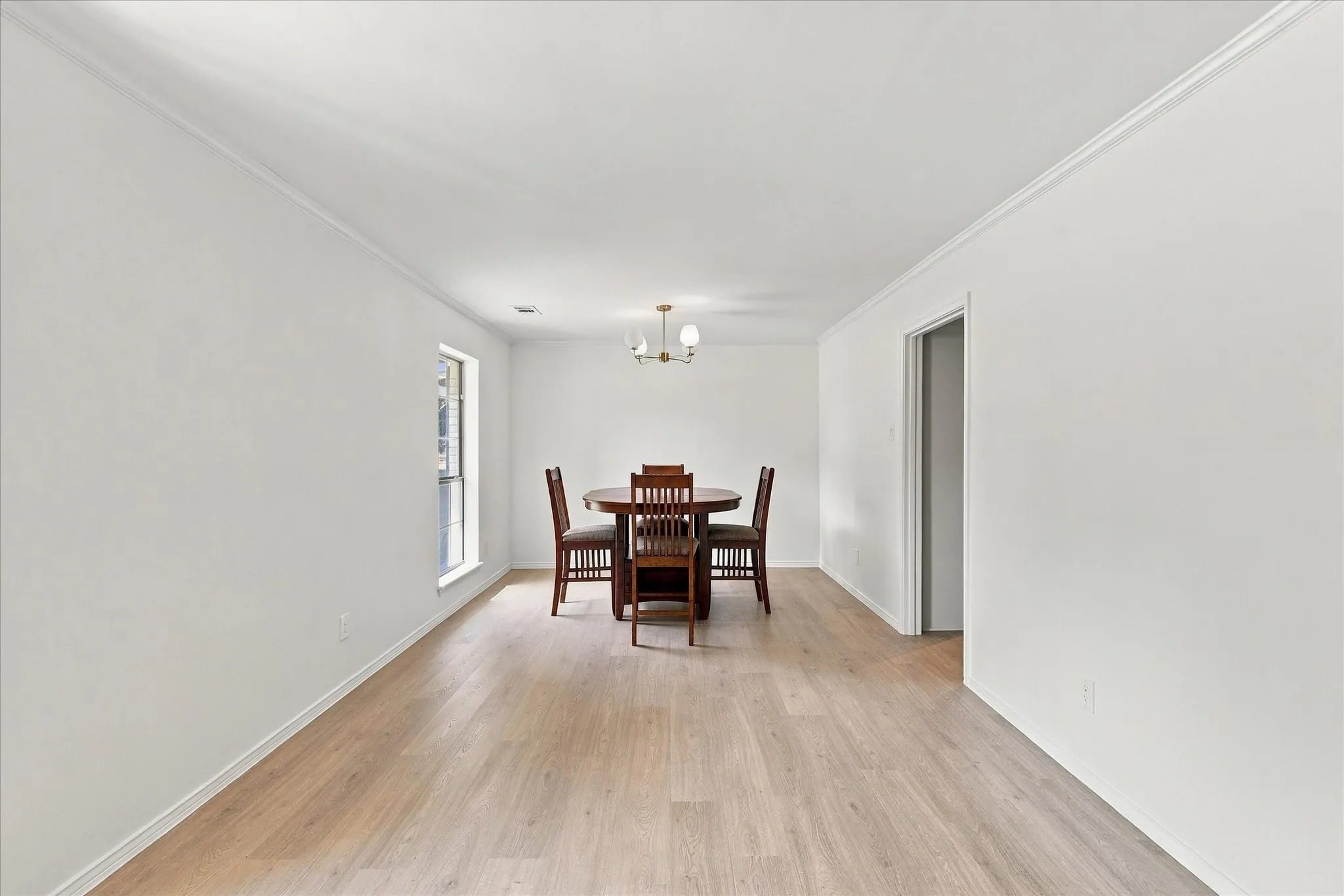 Light wood-finish flooring, white walls, and crown molding