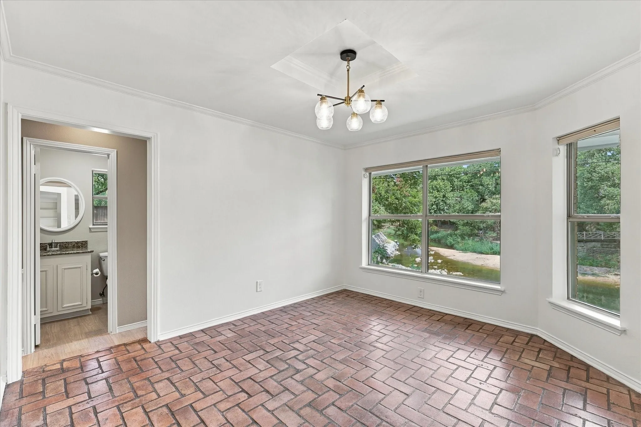 Brick flooring, multiple windows, contemporary chandelier, crown molding