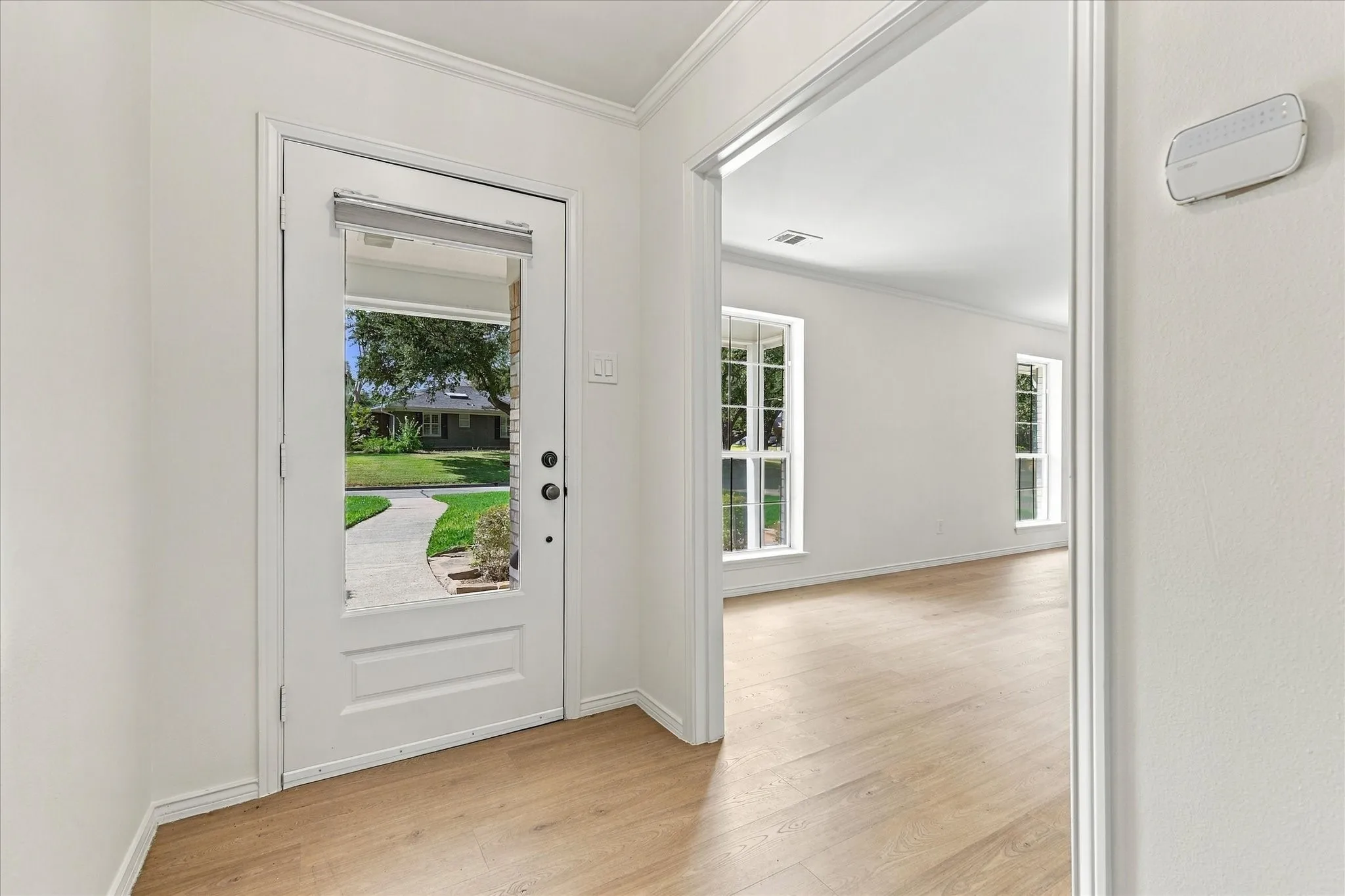 Transitional entryway with wood-finish flooring, white walls, and a full-light entry door
