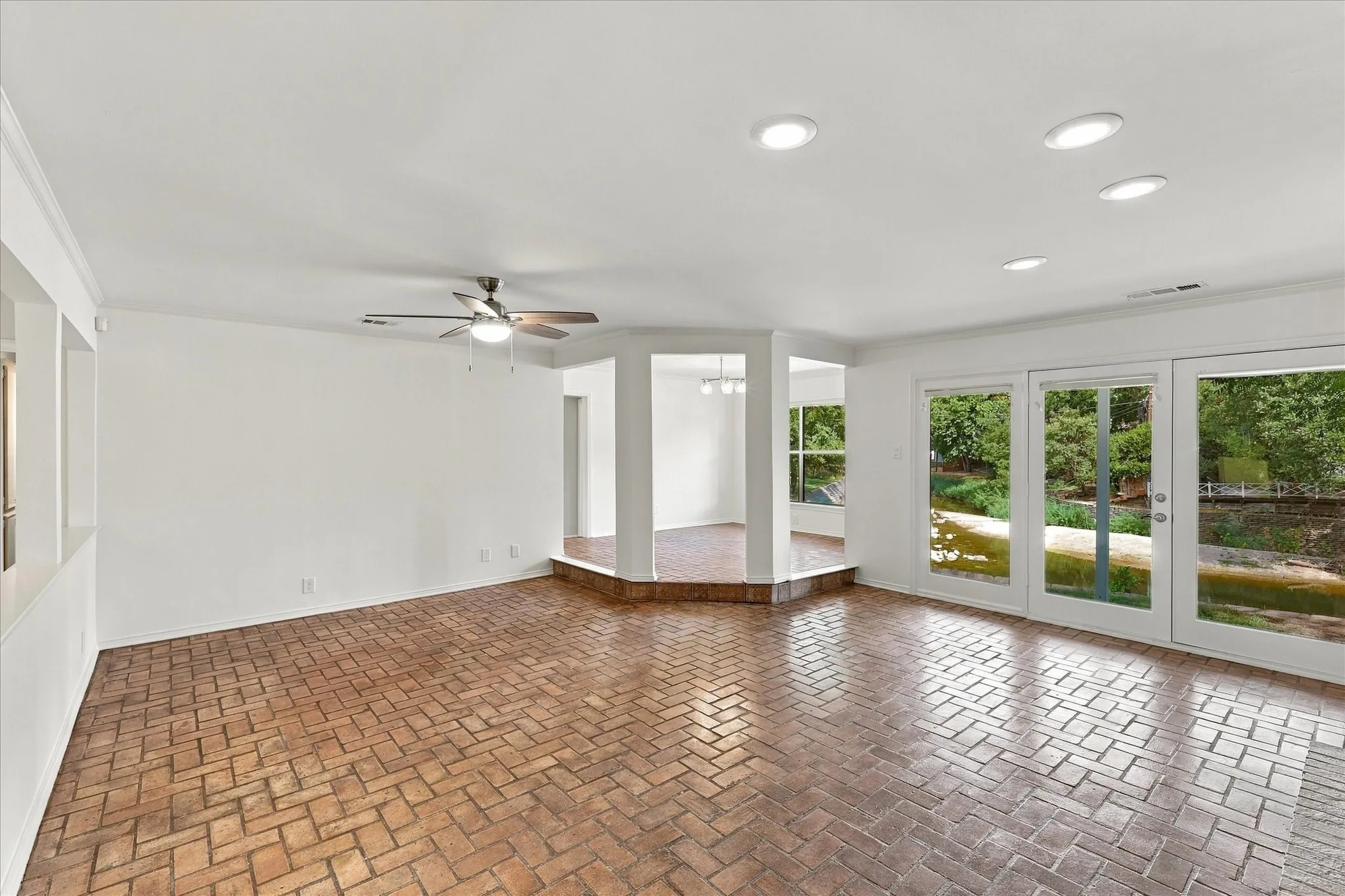 Brick flooring throughout, with a ceiling fan and recessed lighting