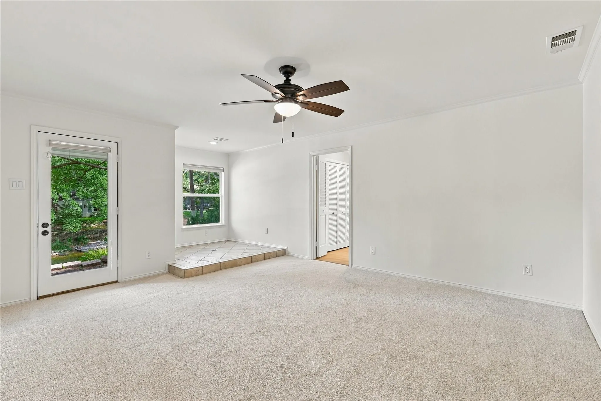 Neutral carpeting, white painted walls, and a ceiling fan with integrated lighting