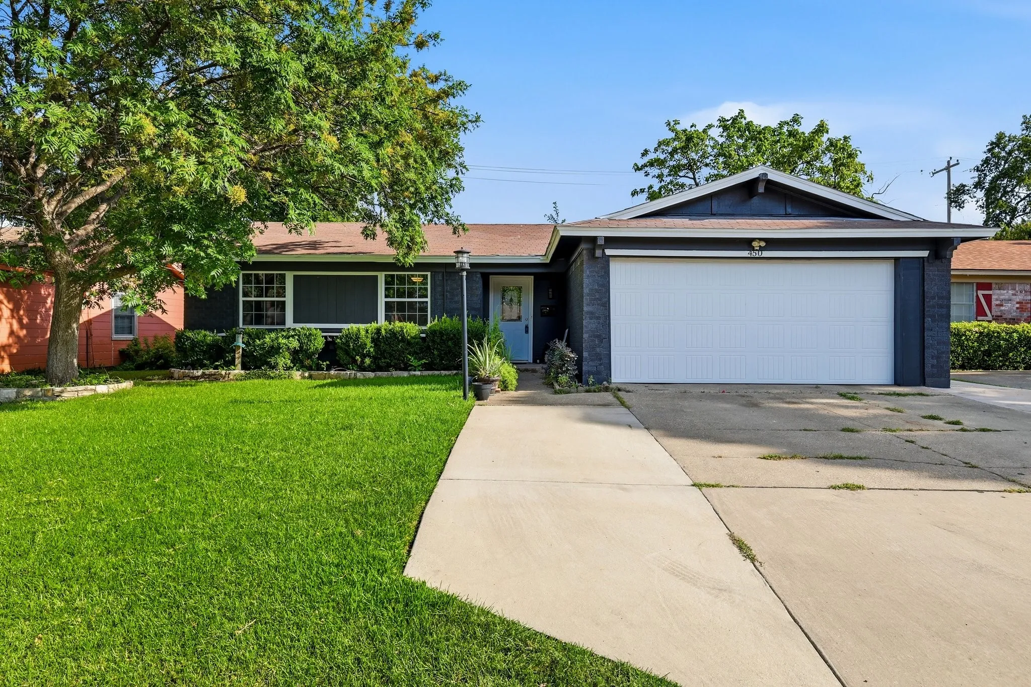 Ranch-style exterior with dark brick veneer, a two-car garage, and an established front lawn