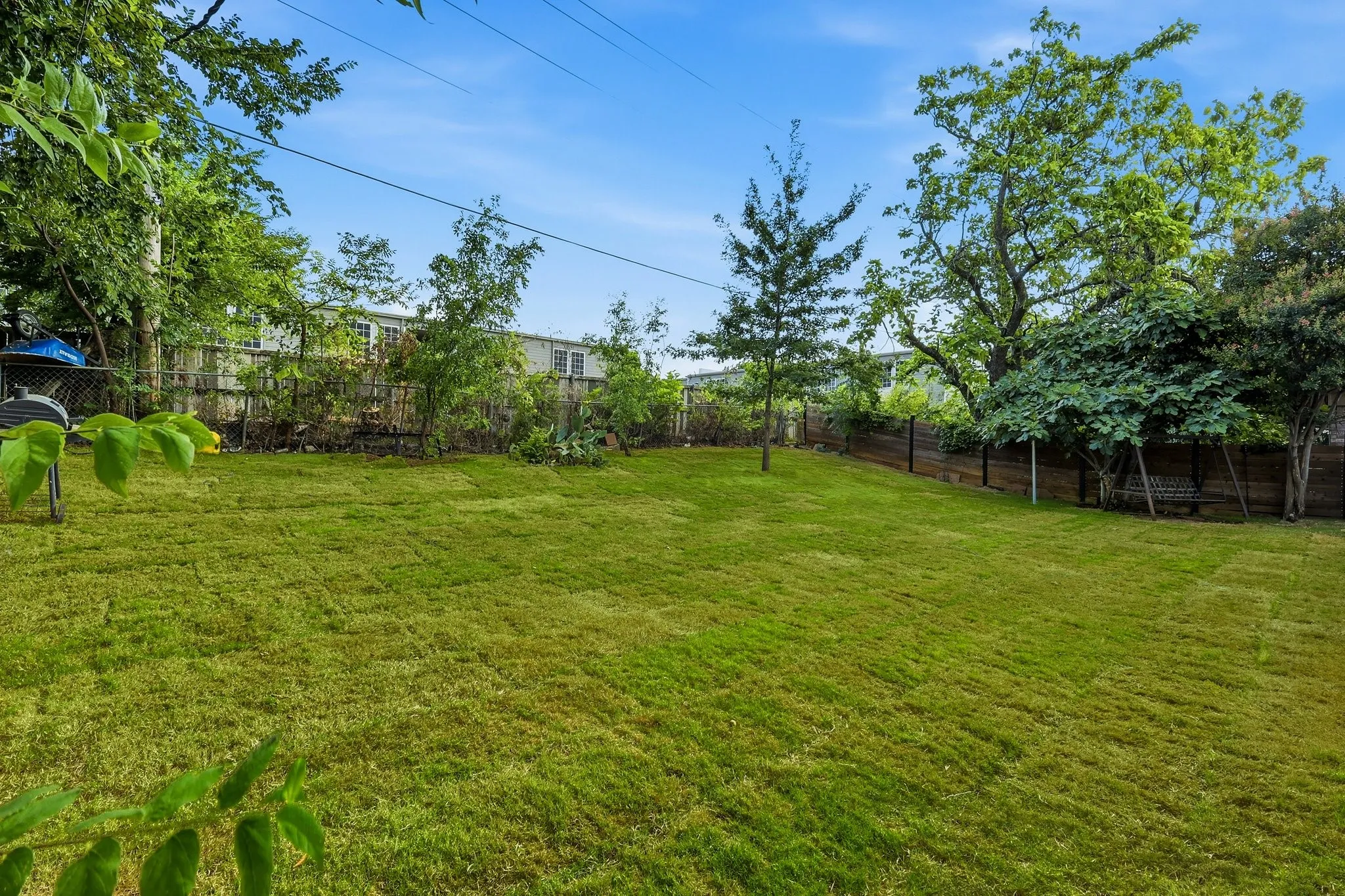 Expansive green lawn with a wood fence perimeter and mature trees