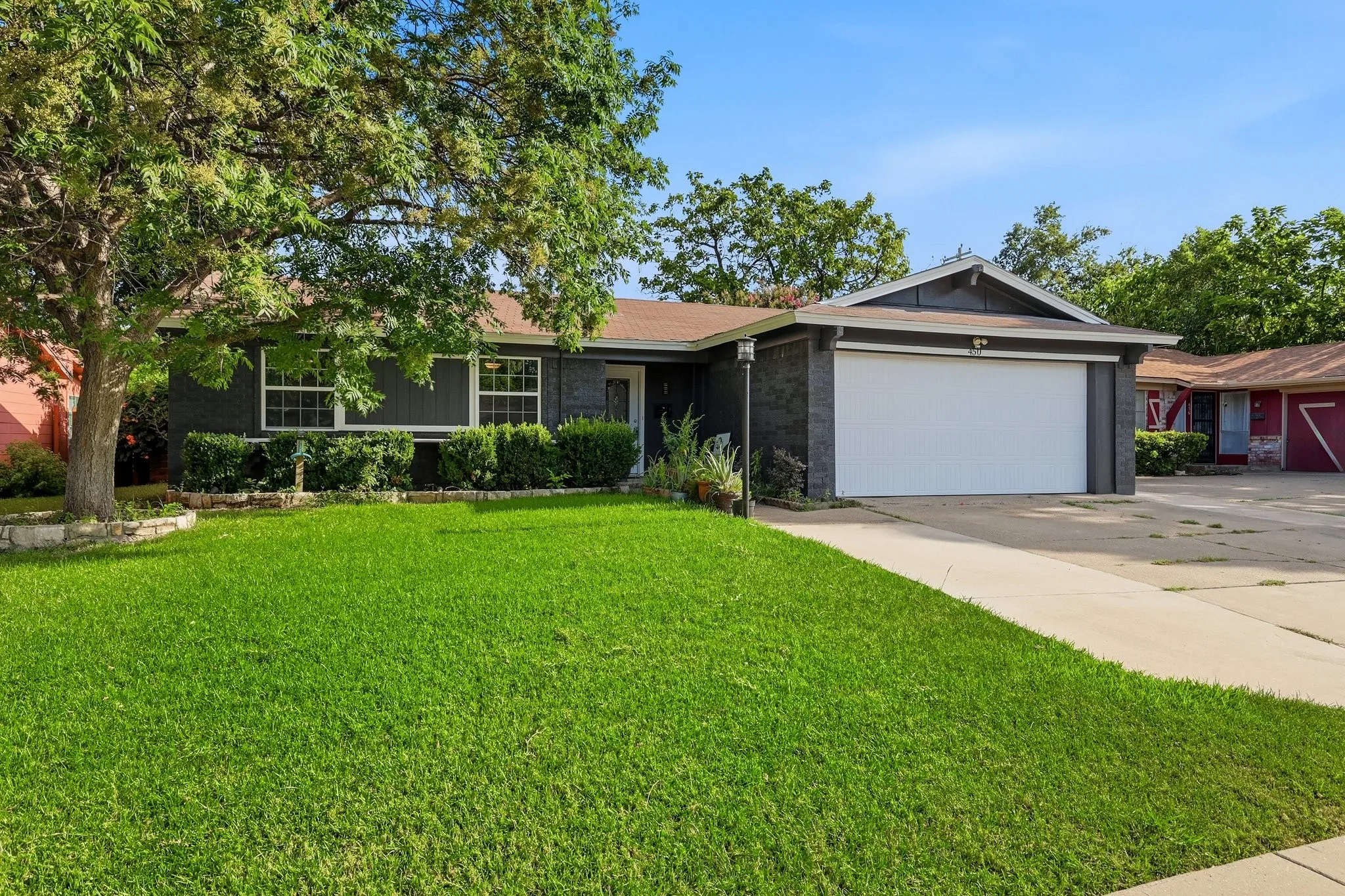 Single-story residence featuring a two-car garage, dark exterior siding, and a contrasting white garage door