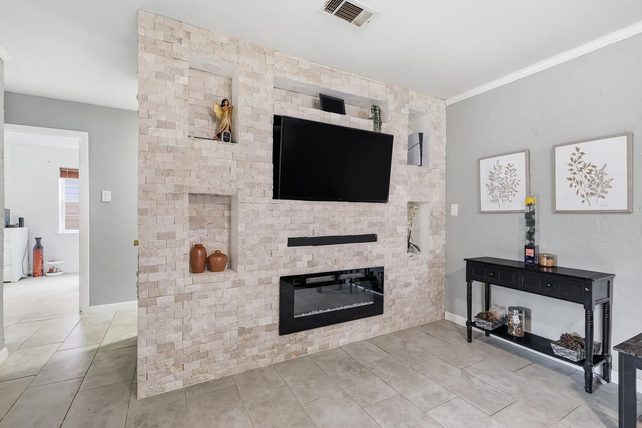 Stone-accented media wall with integrated shelving and an electric fireplace