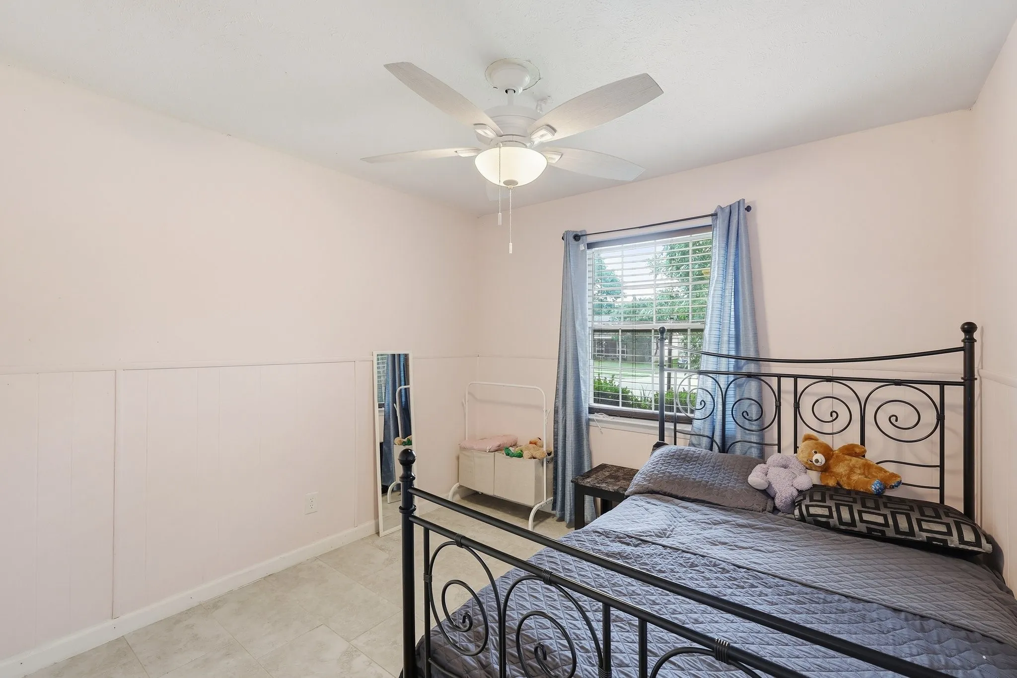 Ceiling fan with integrated lighting, window with blinds, tile flooring, and wall paneling