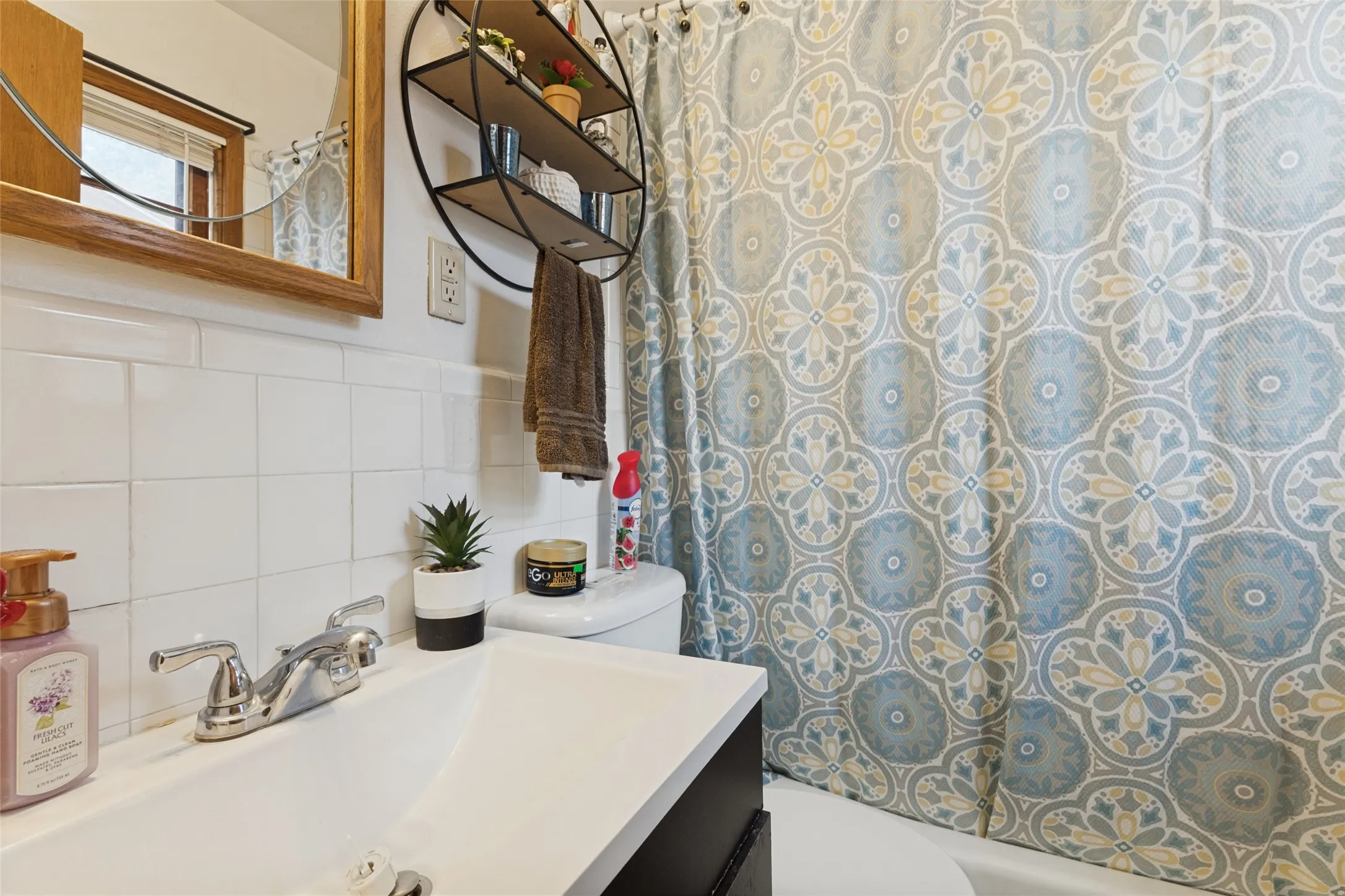 White square tile wainscoting and a wood-framed mirror