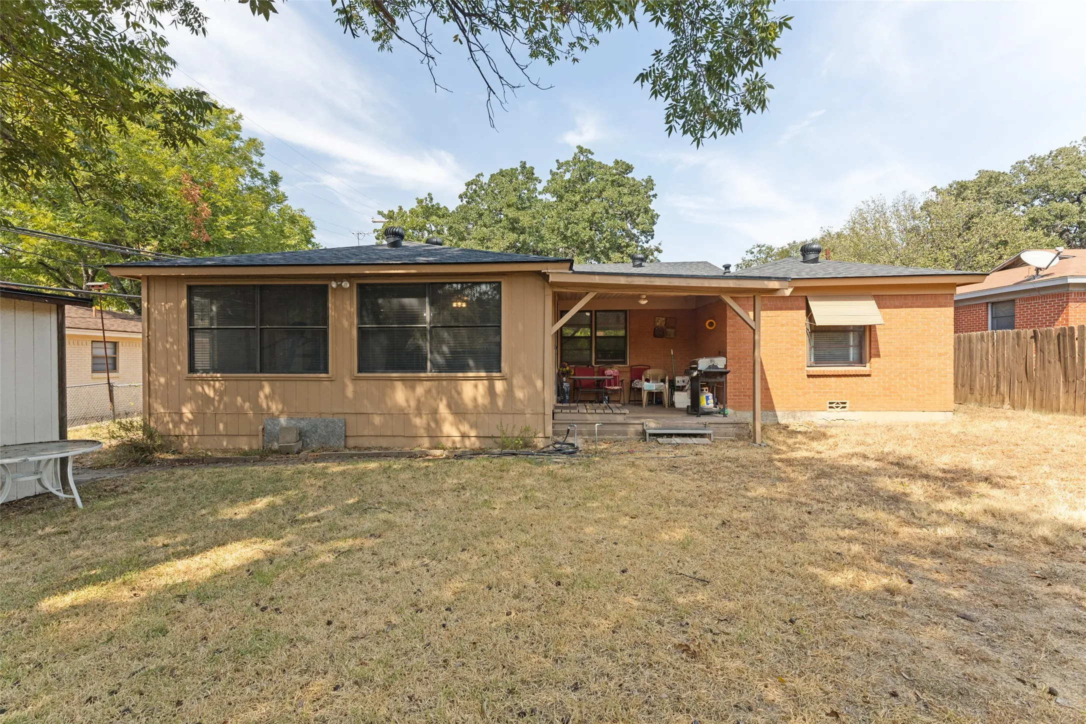 Expansive backyard featuring a covered patio, wood deck, and a storage shed