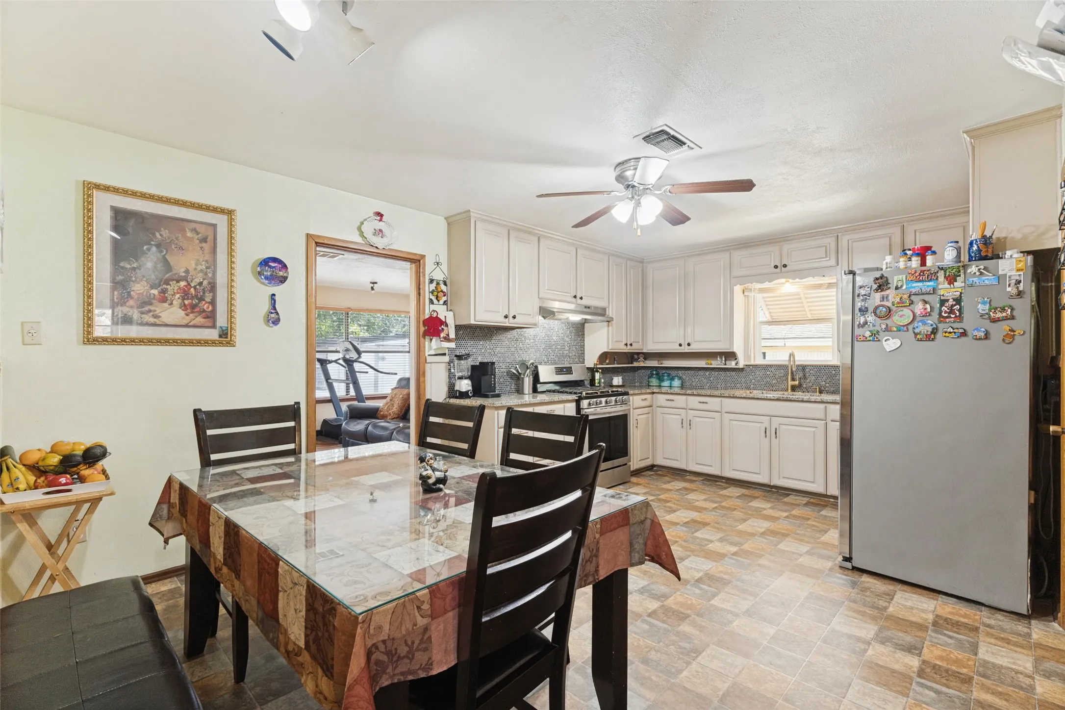 Kitchen featuring white cabinetry, a tile backsplash, stainless steel appliances, and patterned flooring