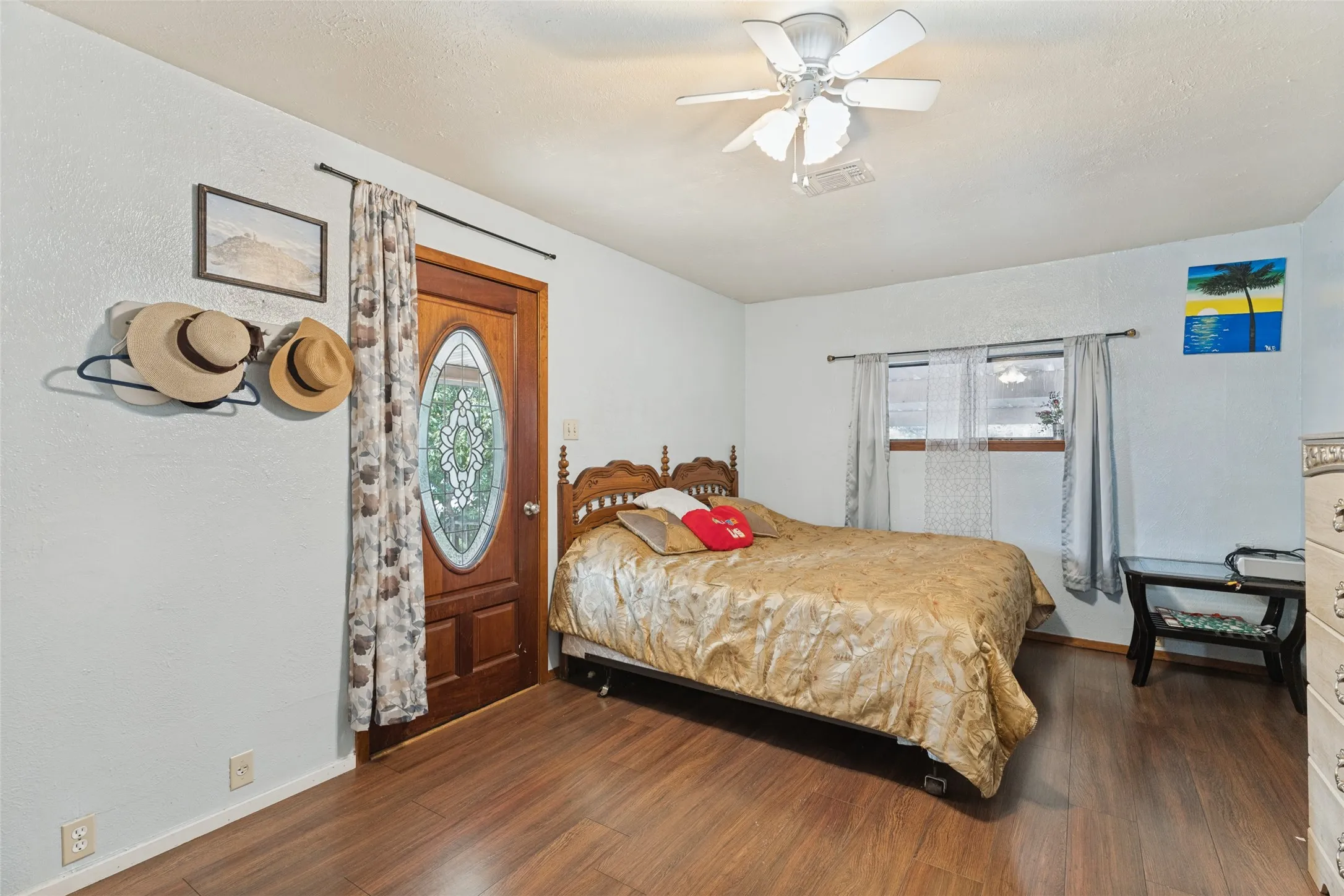 Wood-finish flooring, ceiling fan, and window with wood trim