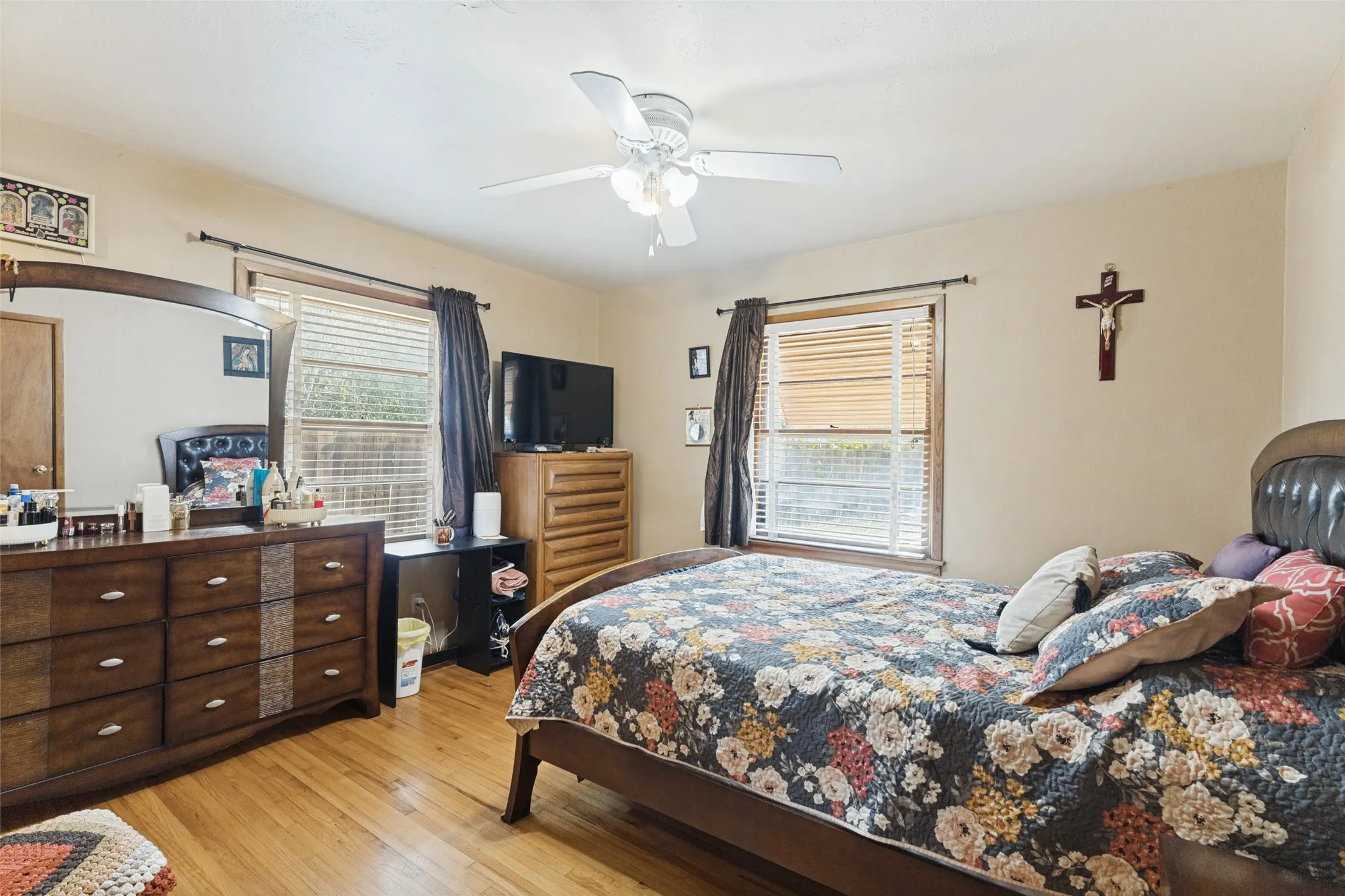 Hardwood flooring, two windows with blinds, ceiling fan, and painted walls