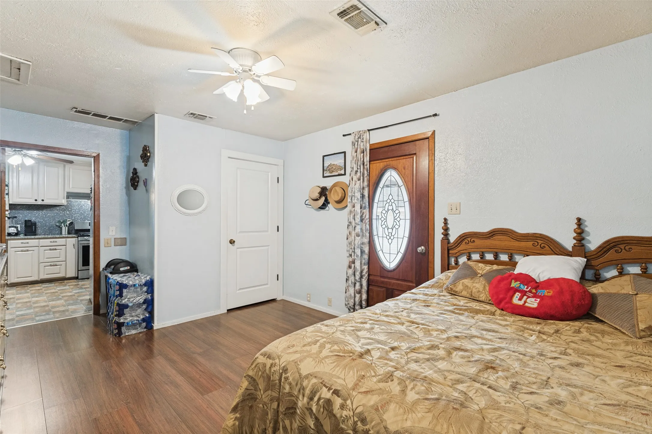 Wood-finish flooring, white ceiling fan, and a wood-panel door with decorative glass inlay
