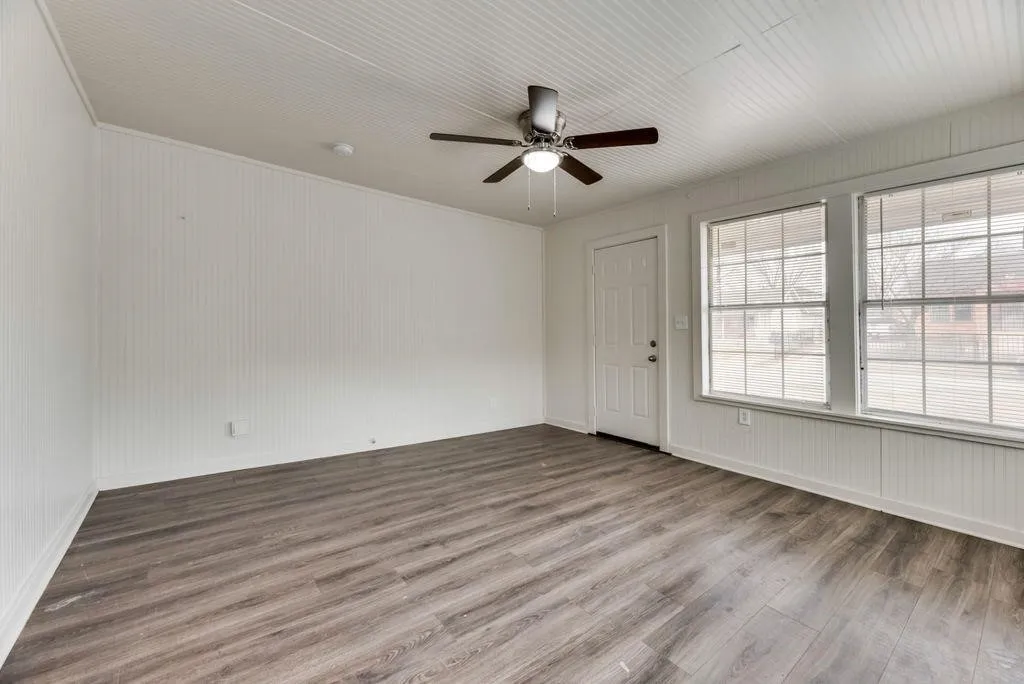 Wood-finish flooring, white beadboard walls, and a white beadboard ceiling with a ceiling fan