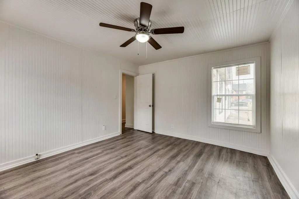 Room featuring wood-finish flooring, white beadboard walls, a white ceiling with beadboard detail, and a ceiling fan with integrated lighting