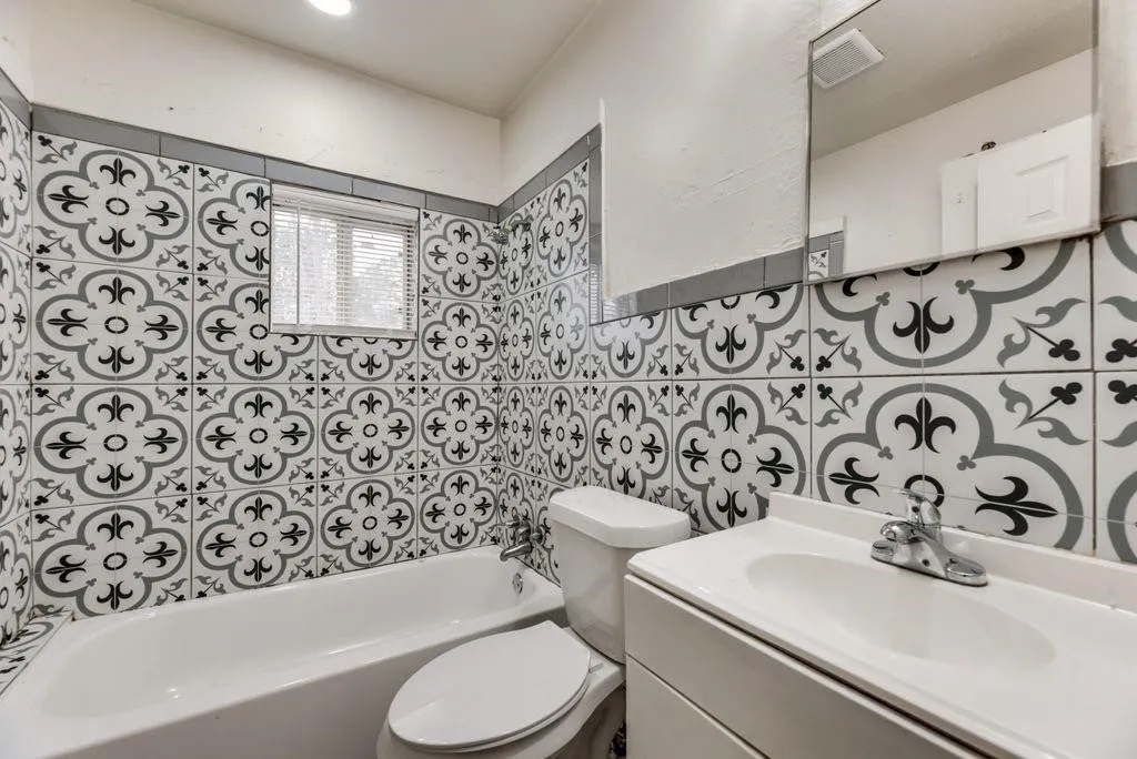 Bathroom featuring decorative wall tile, a built-in bathtub, and a vanity with an integrated sink