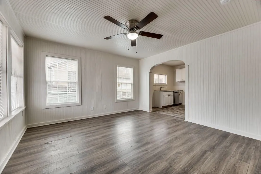 Wood-finish flooring, white beadboard walls, and a ceiling fan with integrated lighting