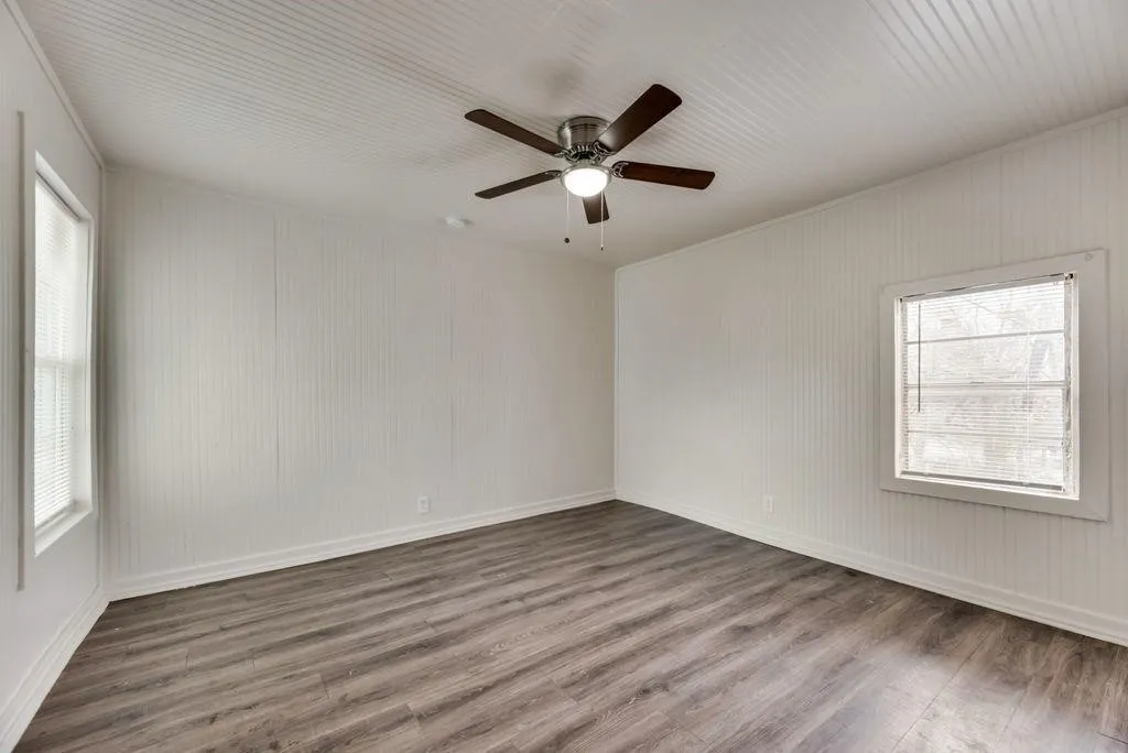 Wood-finish flooring, white beadboard wall panels, and two windows