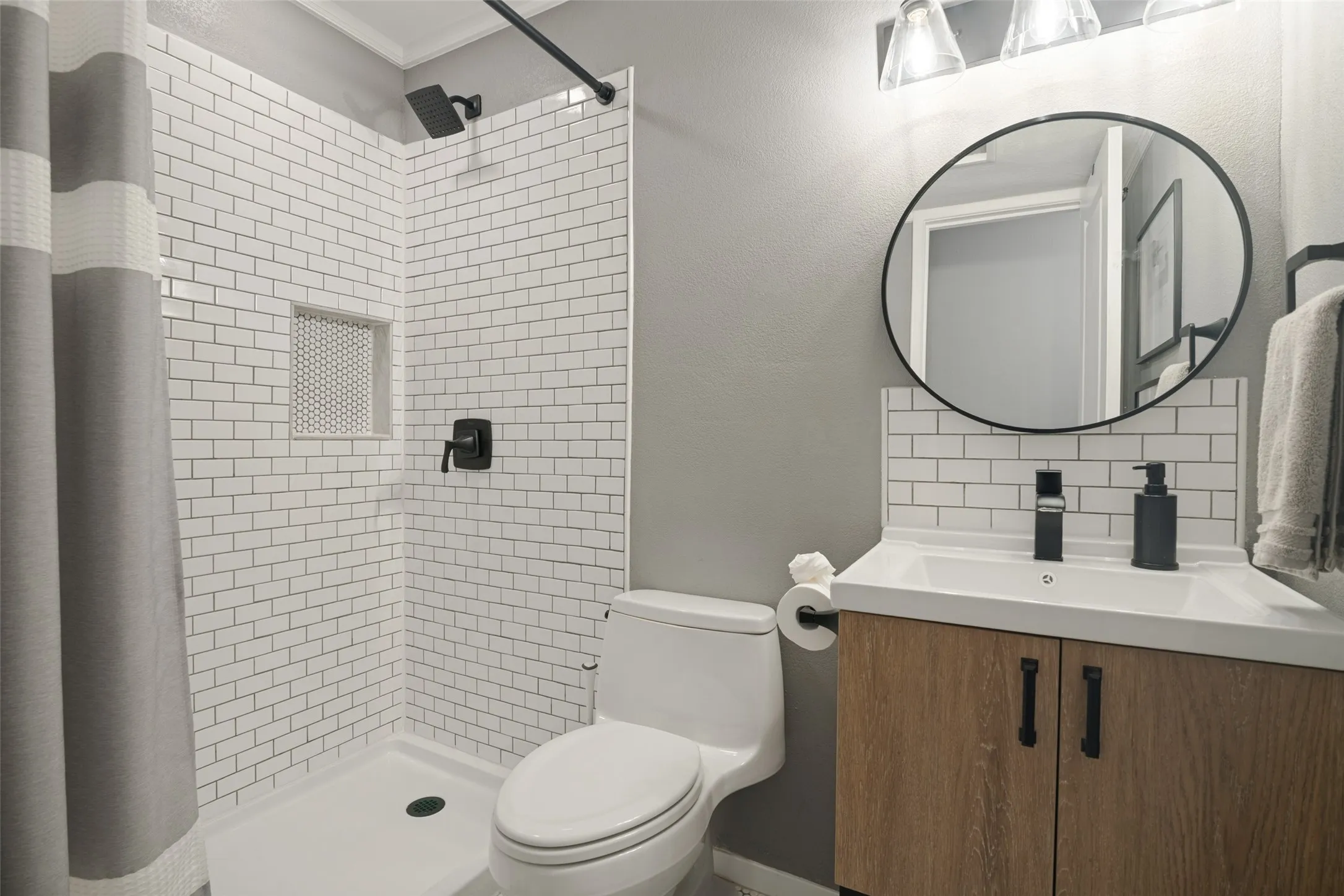 Updated in 2020, the downstairs guest bath features classic white subway tile, a spacious step-in shower, and upgraded lighting, hardware and fixtures.