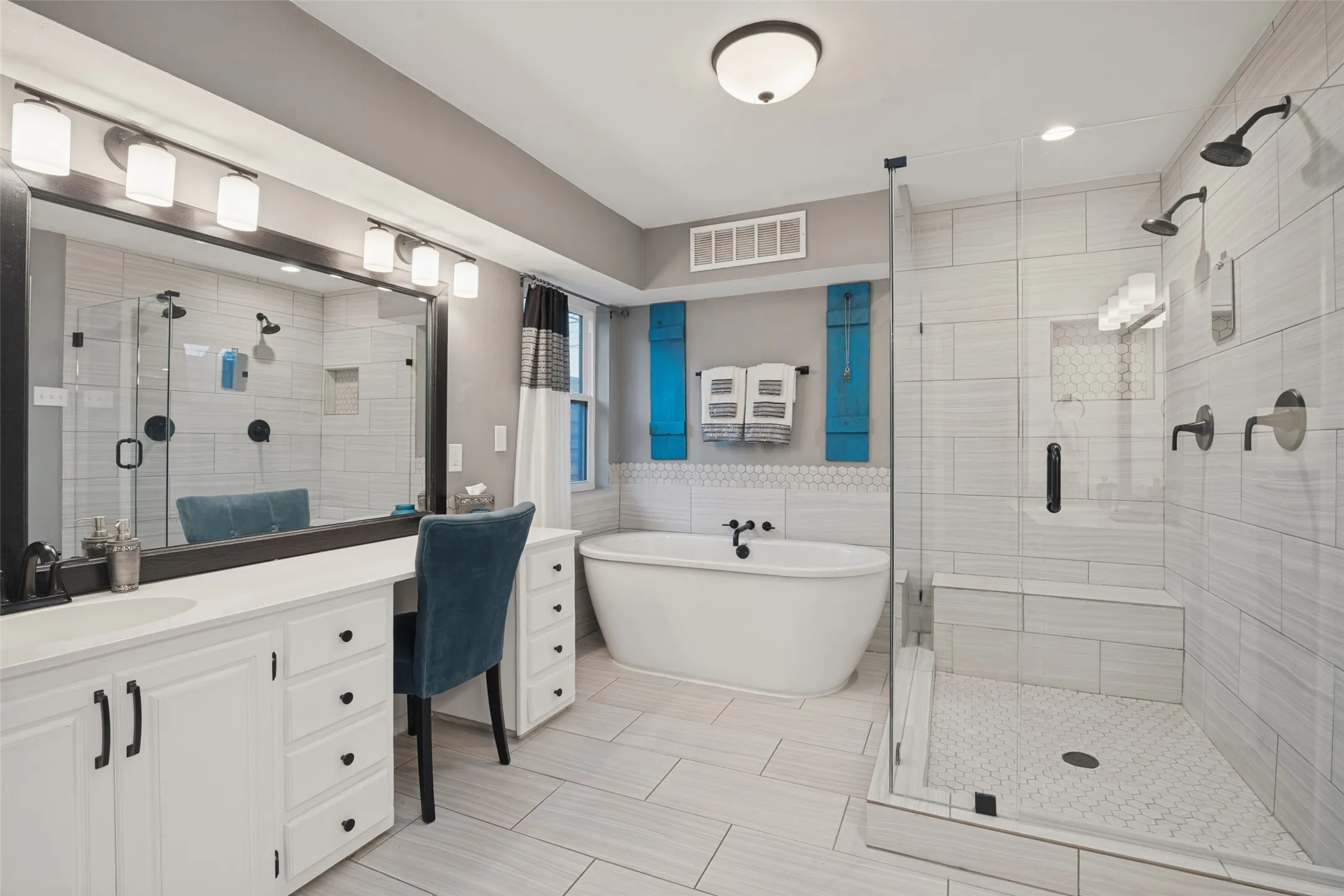 Remodeled in 2021, the primary bath features an oversized, double shower with dual heads, a luxurious soaking tub, custom tile accents, framed mirrors, and updated lighting and hardware.