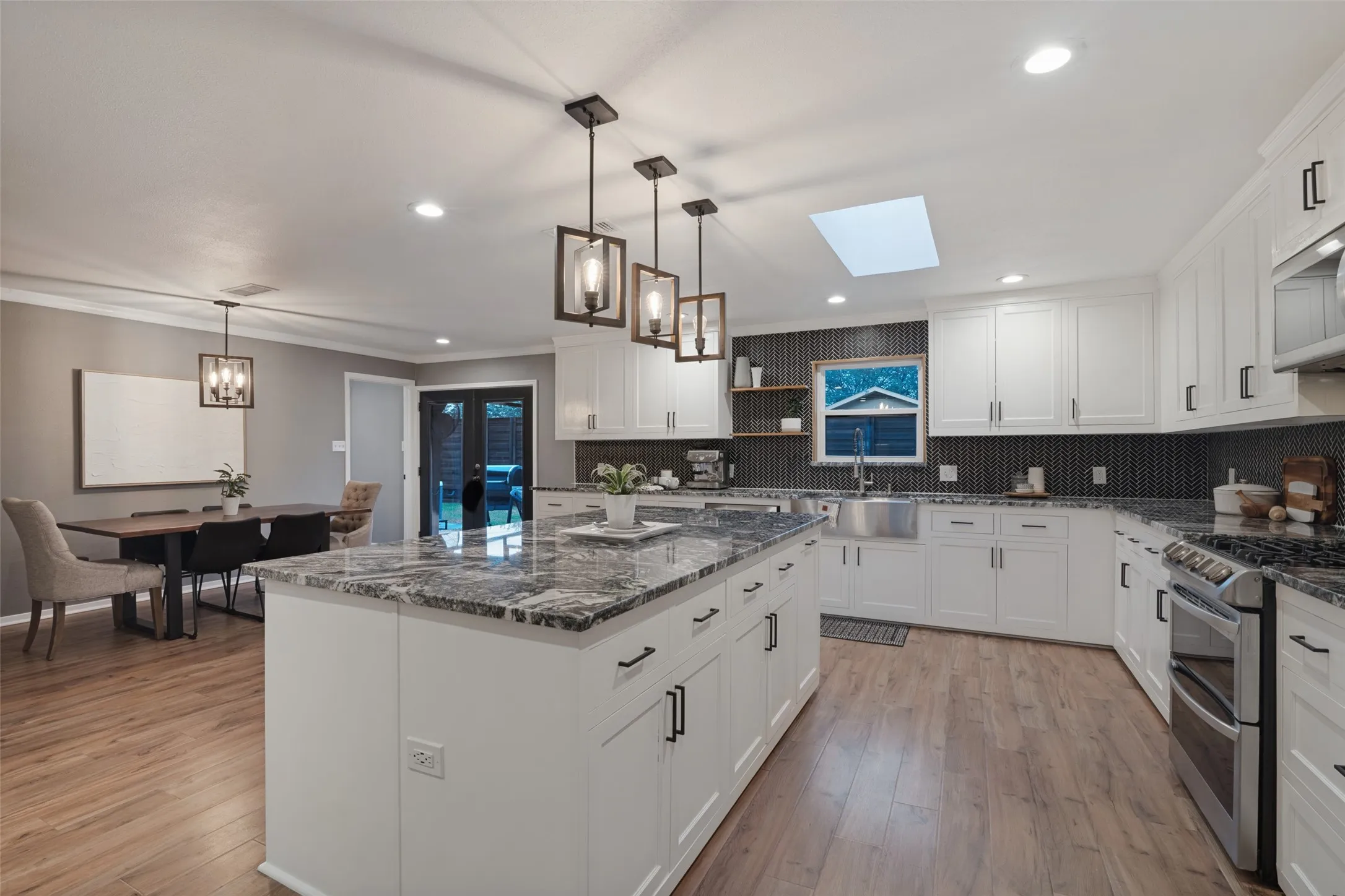 Truly the heart of this home is the amazing chef's kitchen, completely remodeled and expanded in 2021, featuring an abundance of custom cabinetry, oversized island including lots of prep space, sleek granite counter tops, accent lighting, stainless steel appliances, gas cooking, double ovens, and a beautiful stainless steel farm sink.