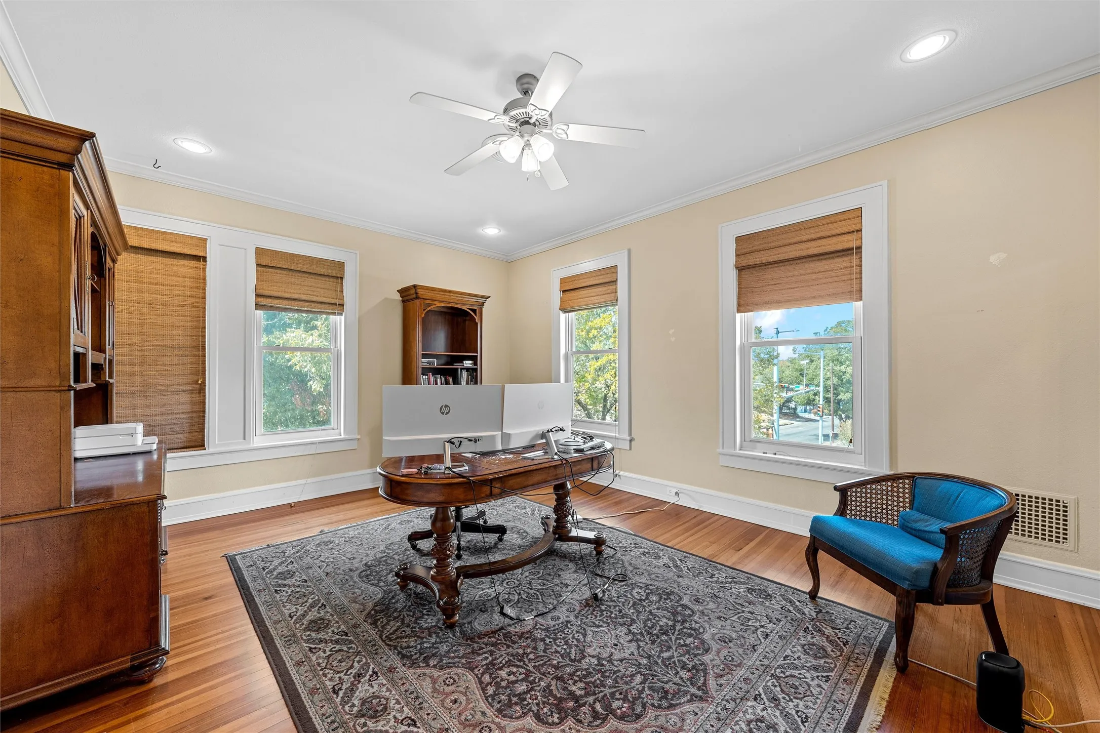 Hardwood flooring paired with crown molding, recessed lighting, and a ceiling fan