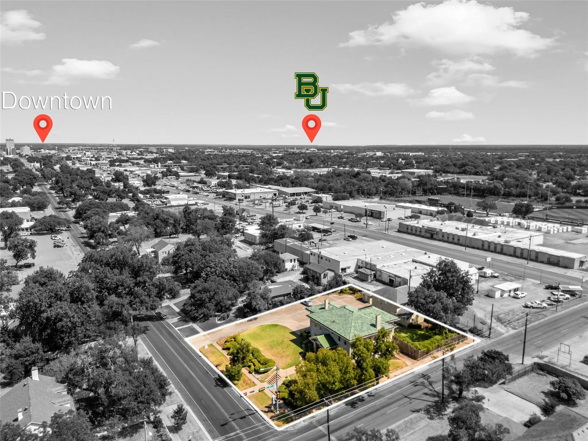 Aerial perspective showcasing a property with a distinctive green roof, surrounded by mature trees and landscaped grounds