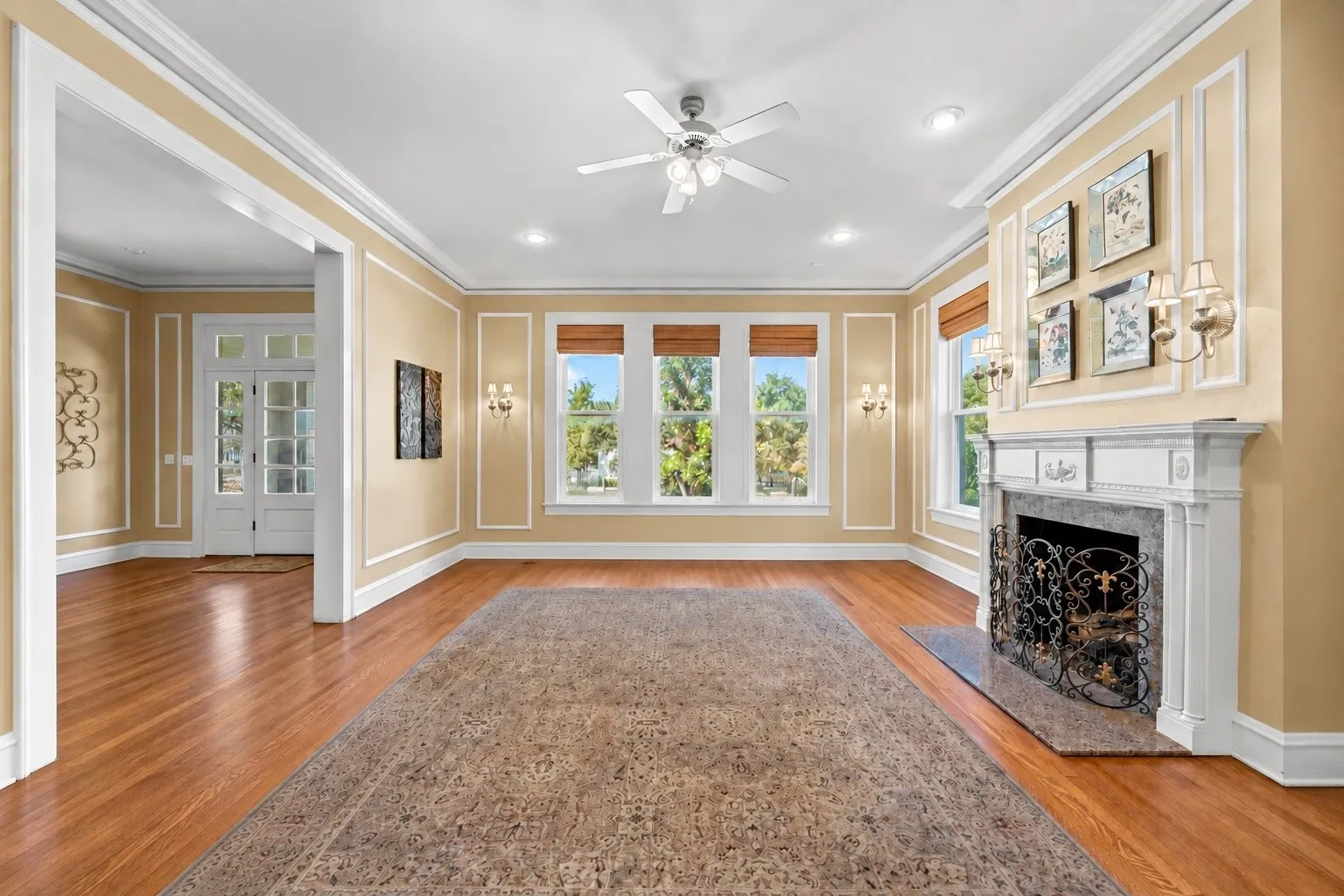 Hardwood flooring, decorative wall molding, fireplace with an ornate mantel, multiple windows, and recessed lighting