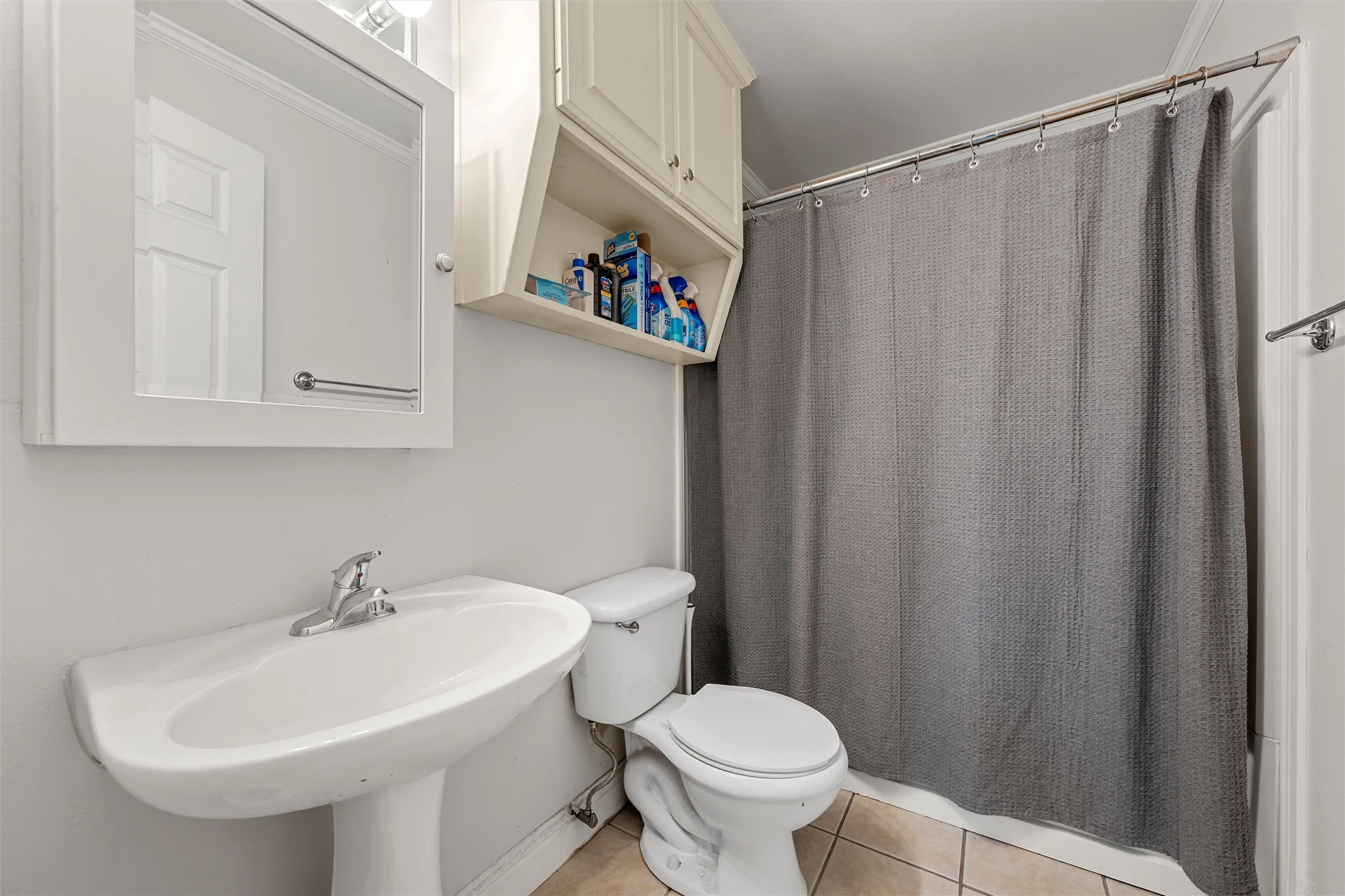Bathroom featuring a pedestal sink, white toilet, and tile flooring