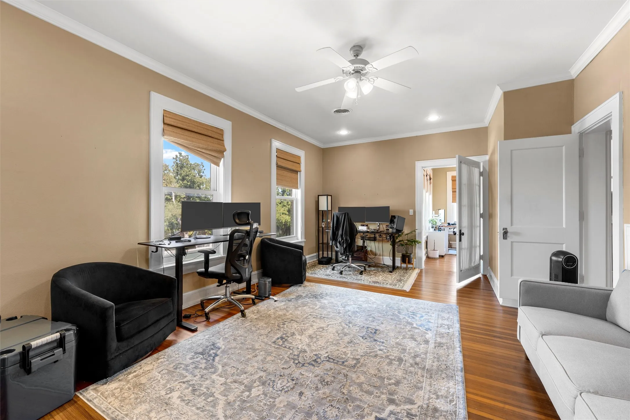 Hardwood flooring, crown molding, ceiling fan, recessed lighting, and multiple windows with blinds